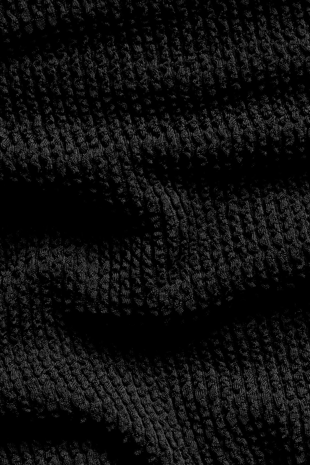 Zbliżenie na czarną, strukturalną tkaninę od dołu bikini.