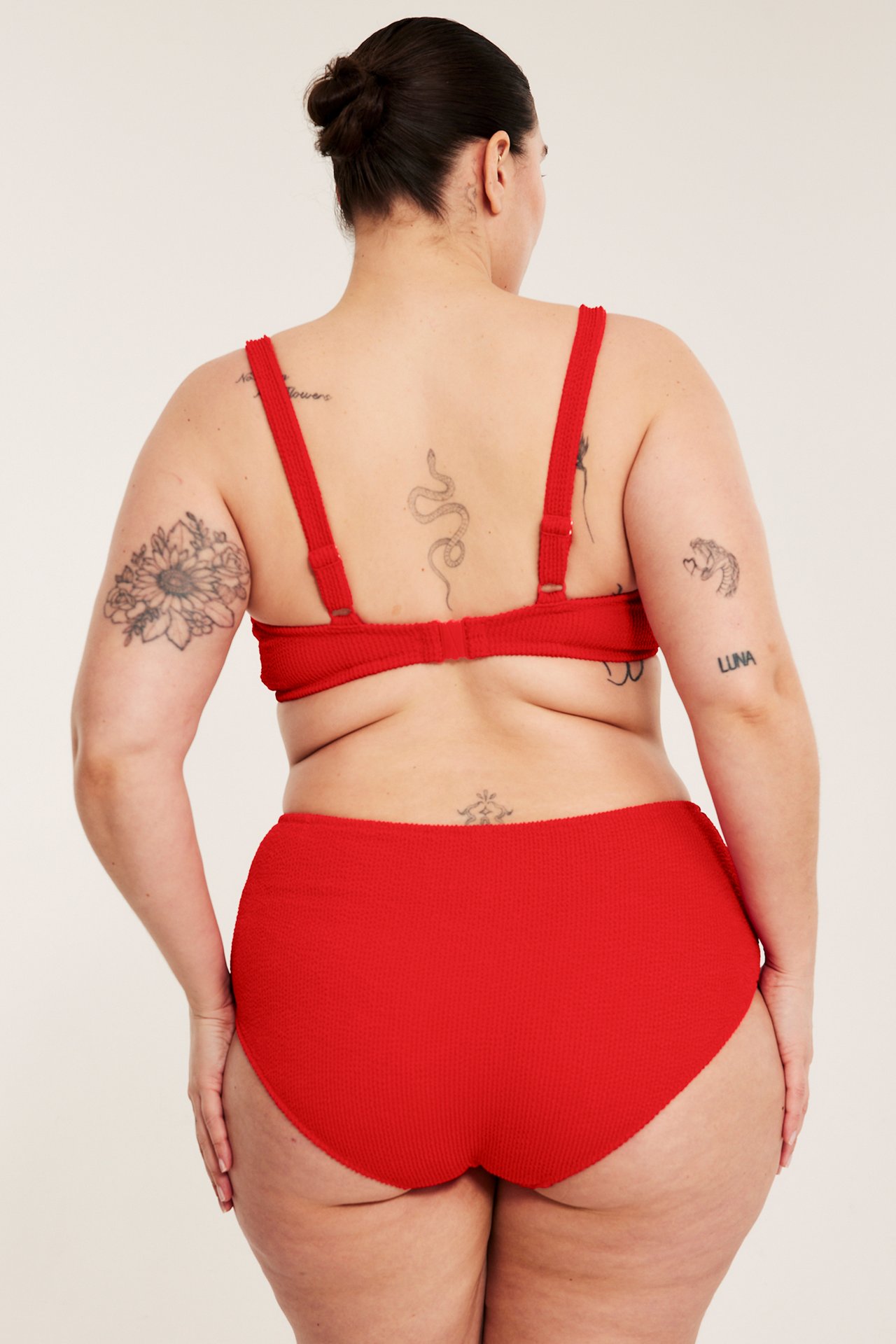 Widok z tyłu kobiety w czerwonych, teksturowanych majtkach bikini typu hipster i pasującym biustonoszu.