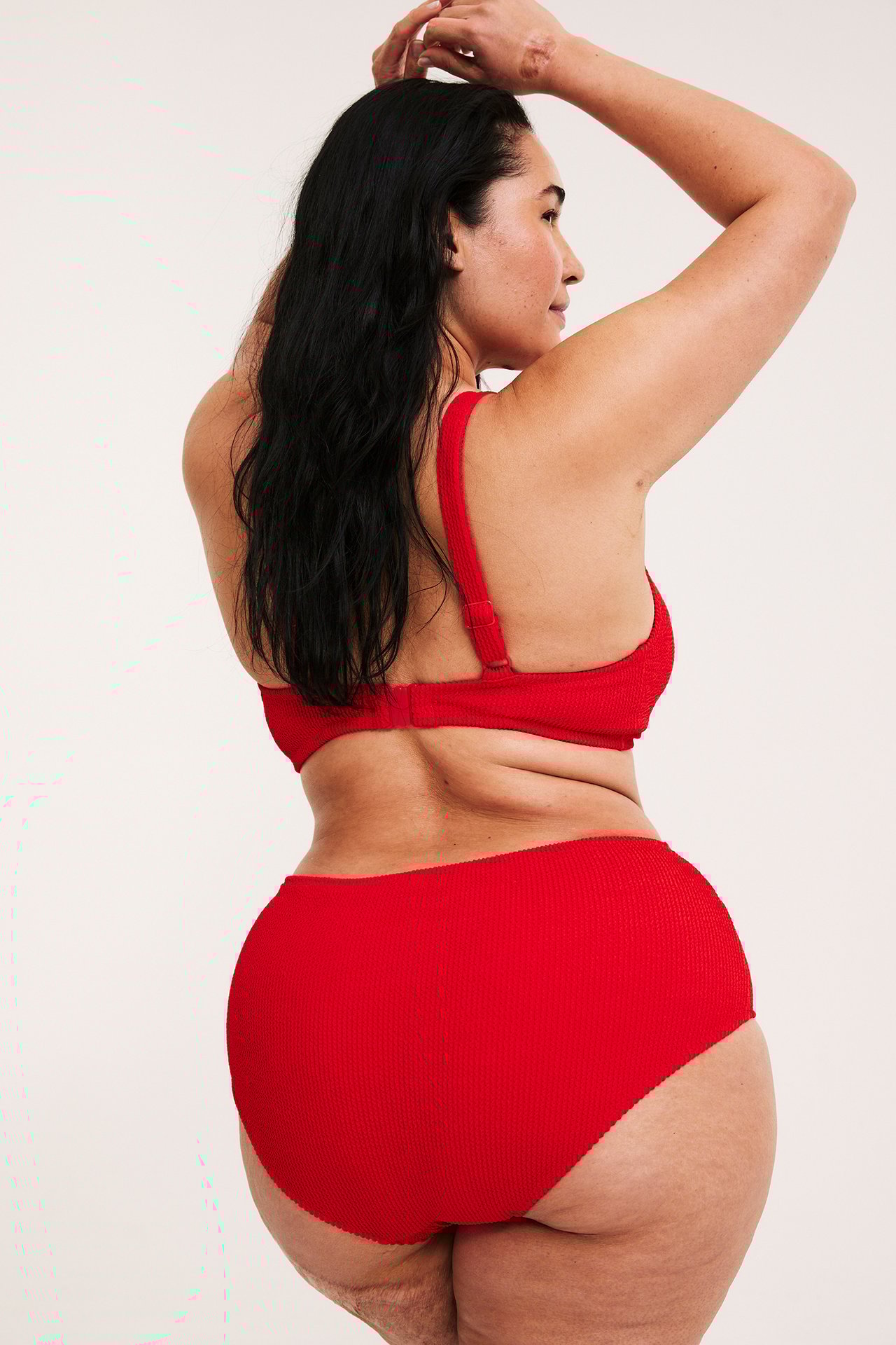 Naisen selkäkuva, yllään punaiset, kuvioidut hipster-bikinialaosat ja yhteensopiva bikinitoppi.