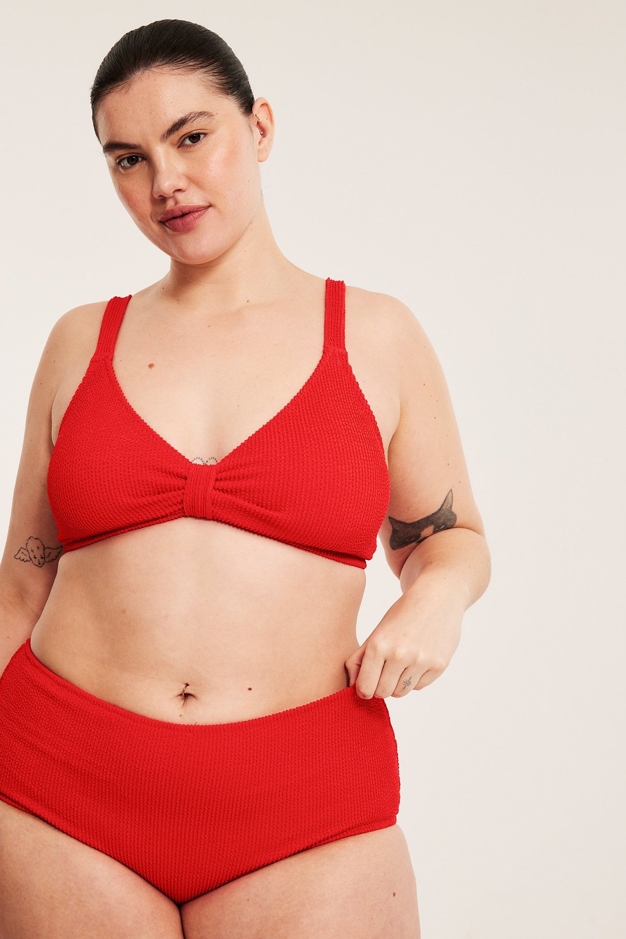 Z przodu: kobieta w czerwonych strukturyzowanych figach bikini, ręka na pasie, pasujący top.