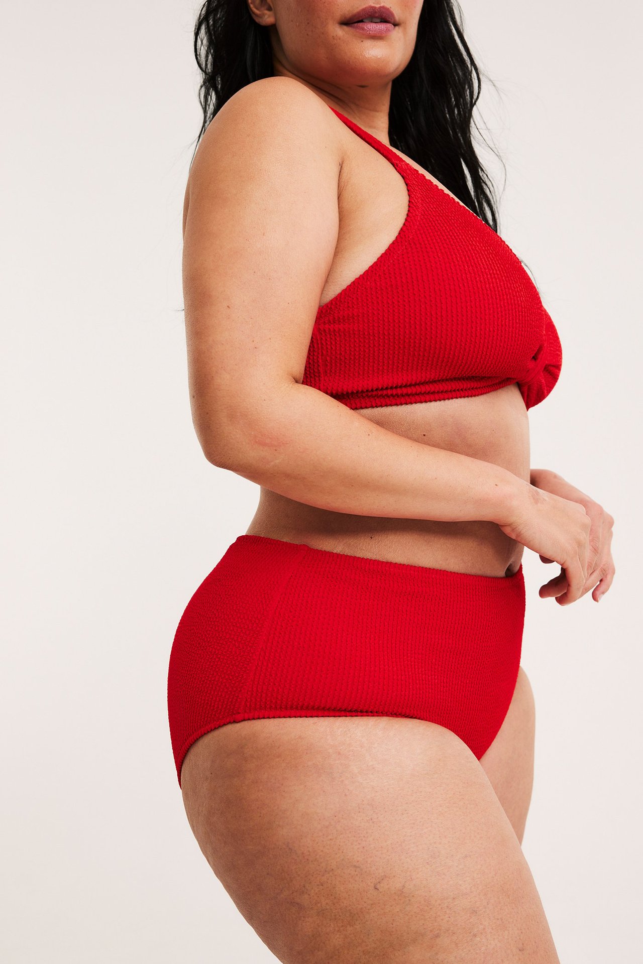 Sivukuva naisesta punaisissa, kuvioiduissa korkeavyötäröisissä bikinin alaosissa ja yhteensopivassa yläosassa.