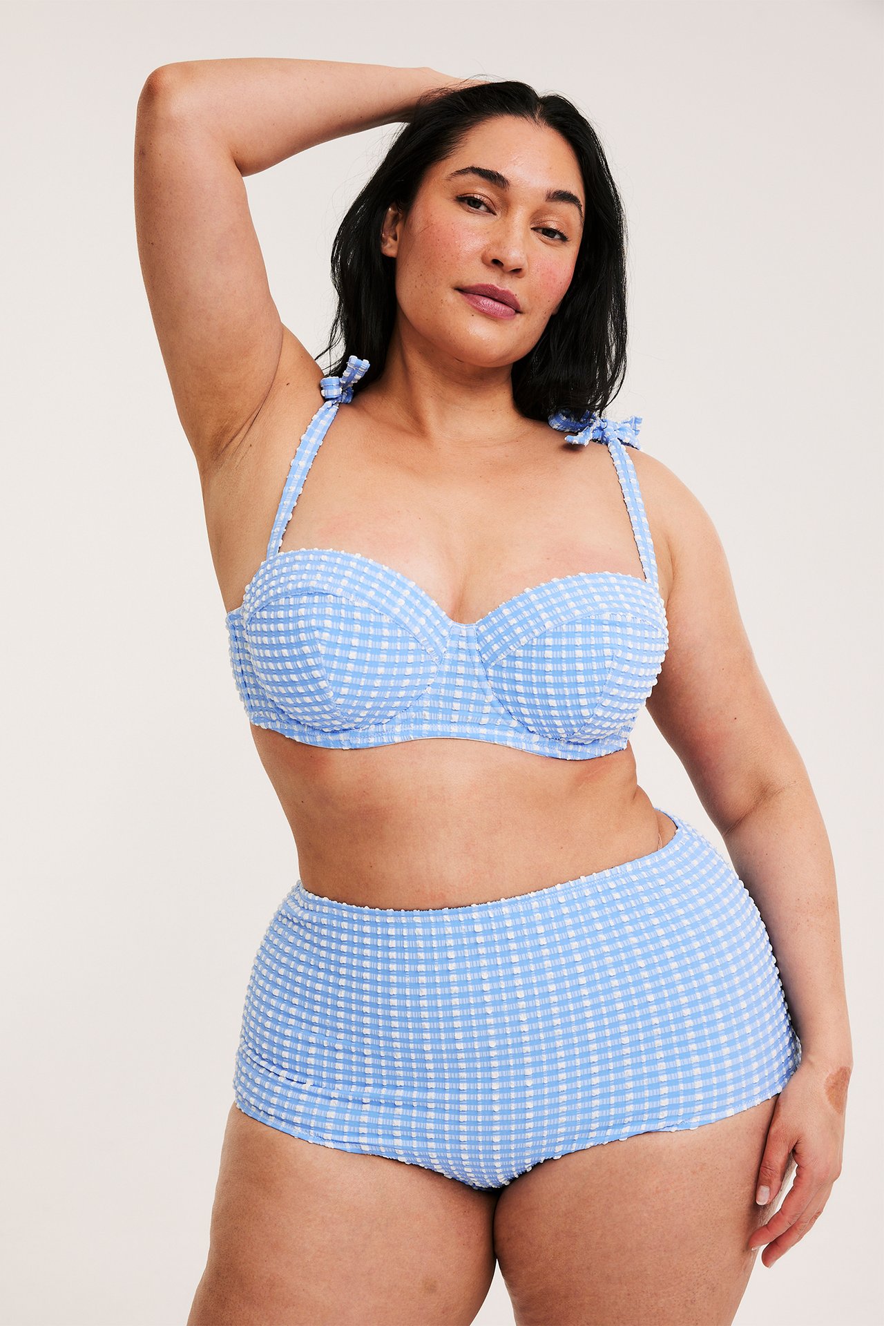 Forfra, kvinne i lyseblå rutete balconette bikini-BH med knytebånd og matchende høy midje bikiniunderdel.