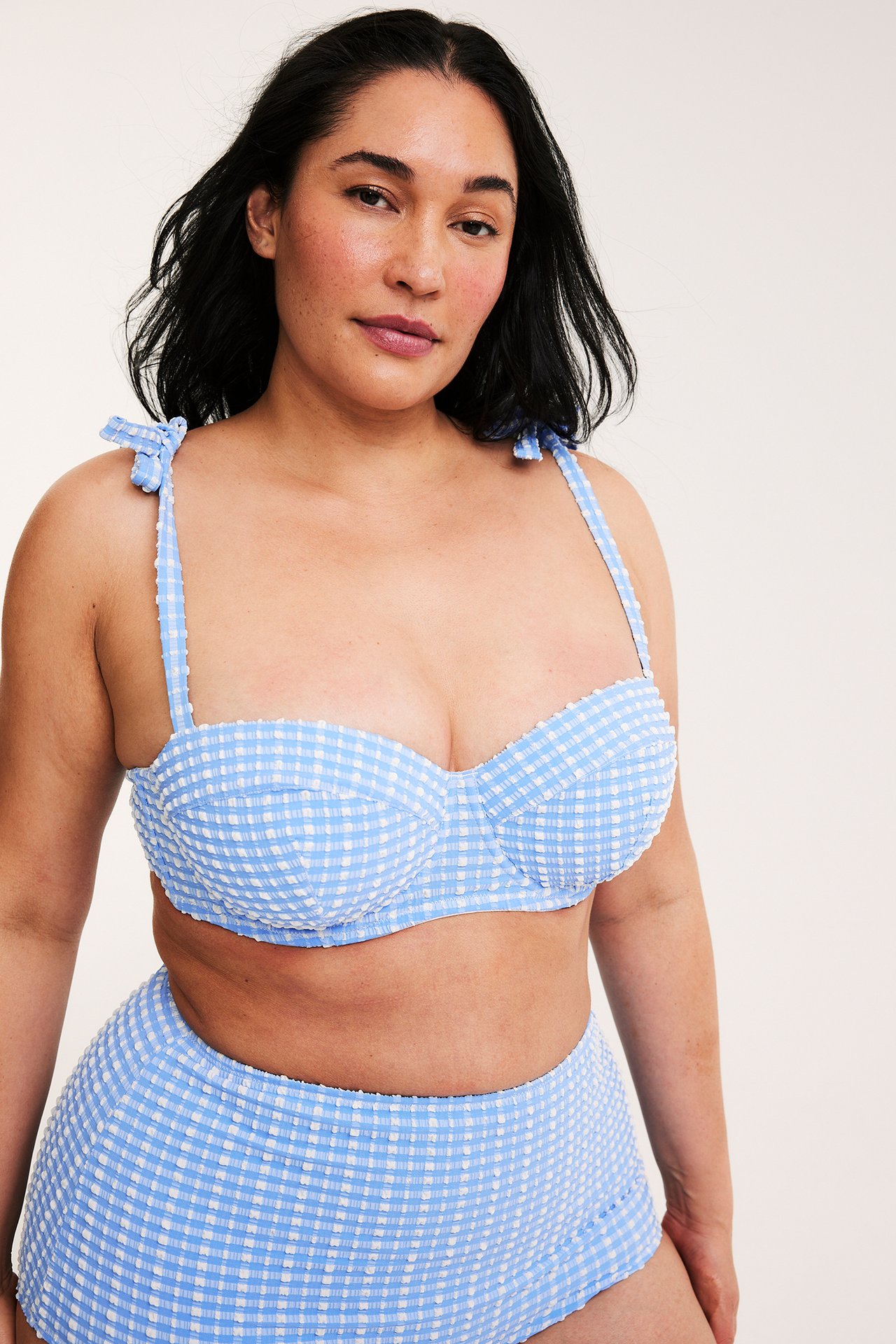 Framsida av kvinna i ljusblåvitrutig balconette bikiniöverdel med knytband och matchande trosa.