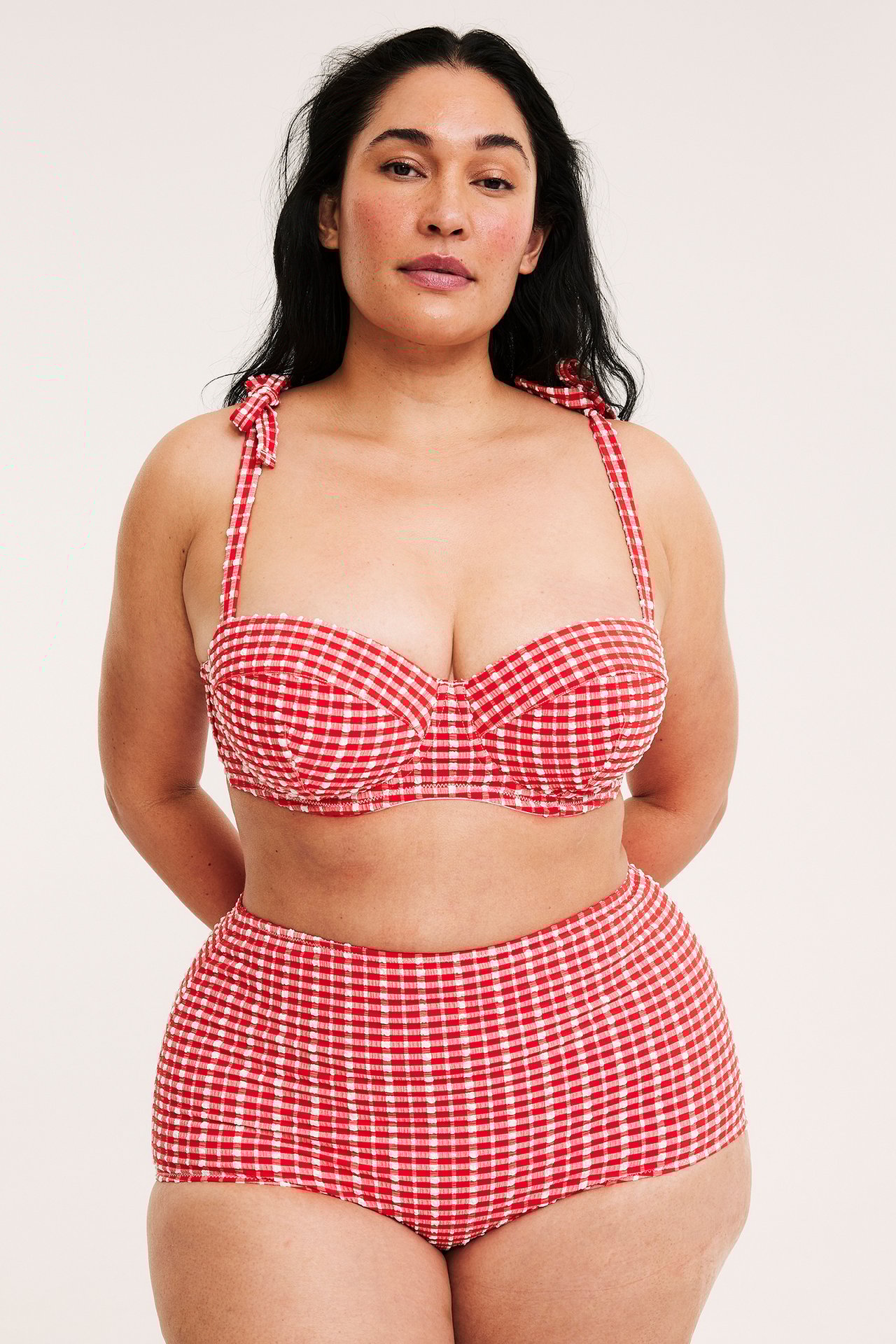 Framifrån: kvinna i rödvitrutig balconettebikini med knytband och höga trosa.