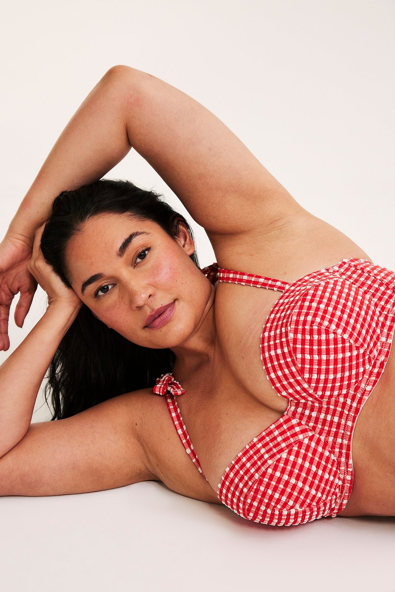 Zbliżenie na kobietę w czerwono-białym, kratkowanym biustonoszu kąpielowym balconette z wiązanymi ramiączkami.