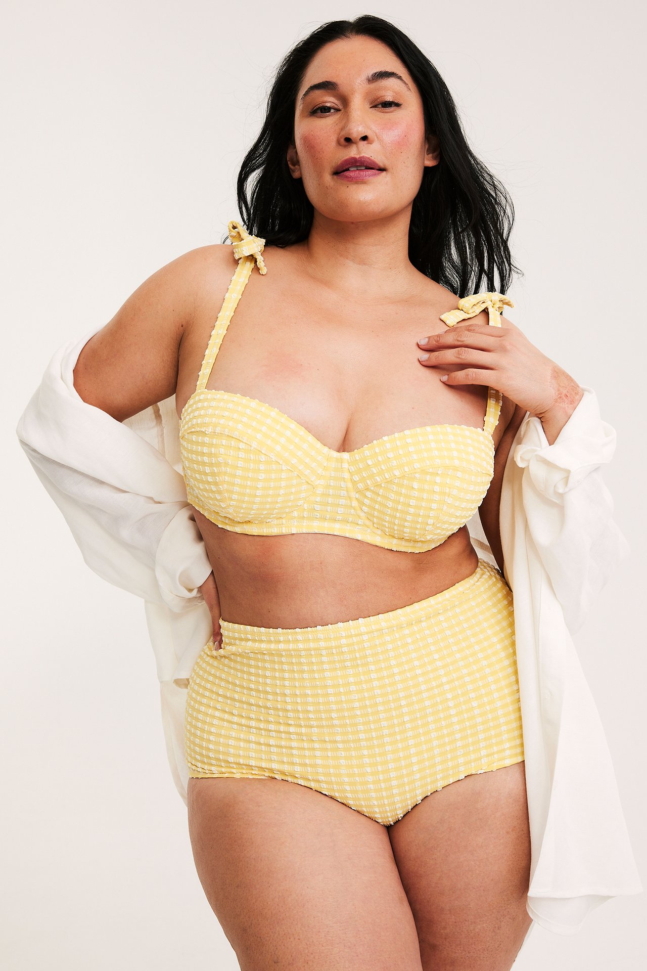 Widok z przodu: kobieta w żółtym biustonoszu kąpielowym balconette, pasujące majtki z wysokim stanem i biała koszula.