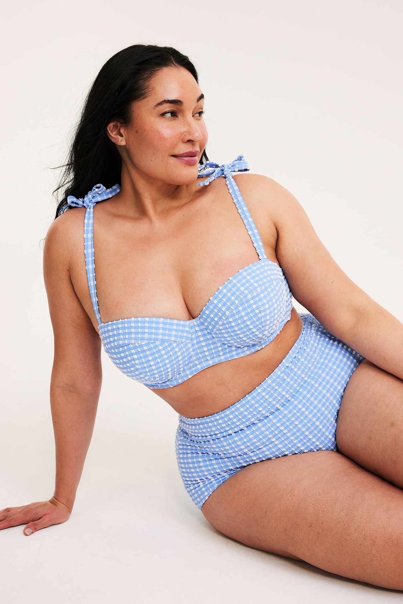 Nainen edestä, yllään ruudullinen vaaleansininen high hipster -bikinihousu ja yhteensopiva yläosa.