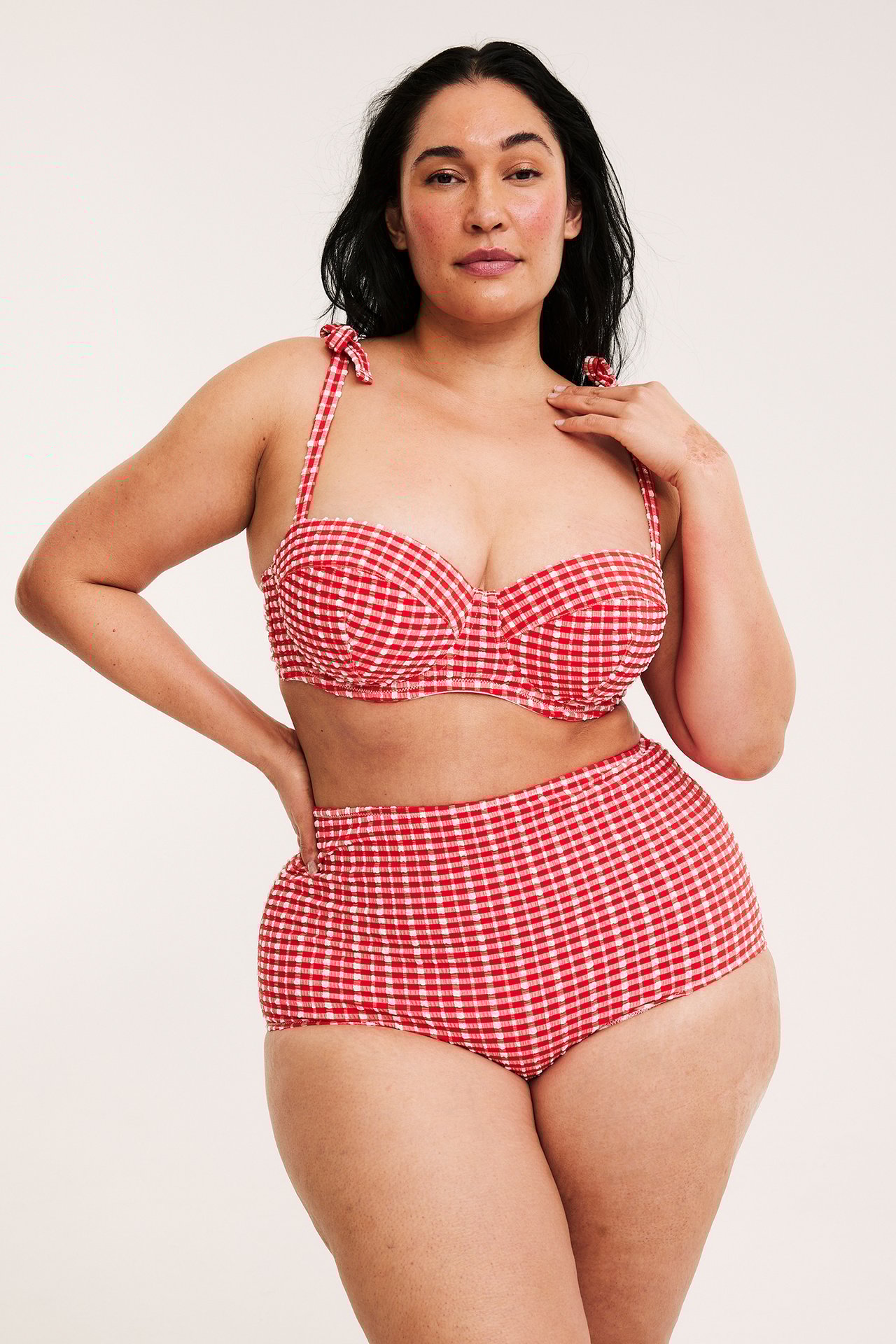 Frontvy: kvinna i rutig röd och vit high hipster bikinitrosa och matchande bikinitopp.