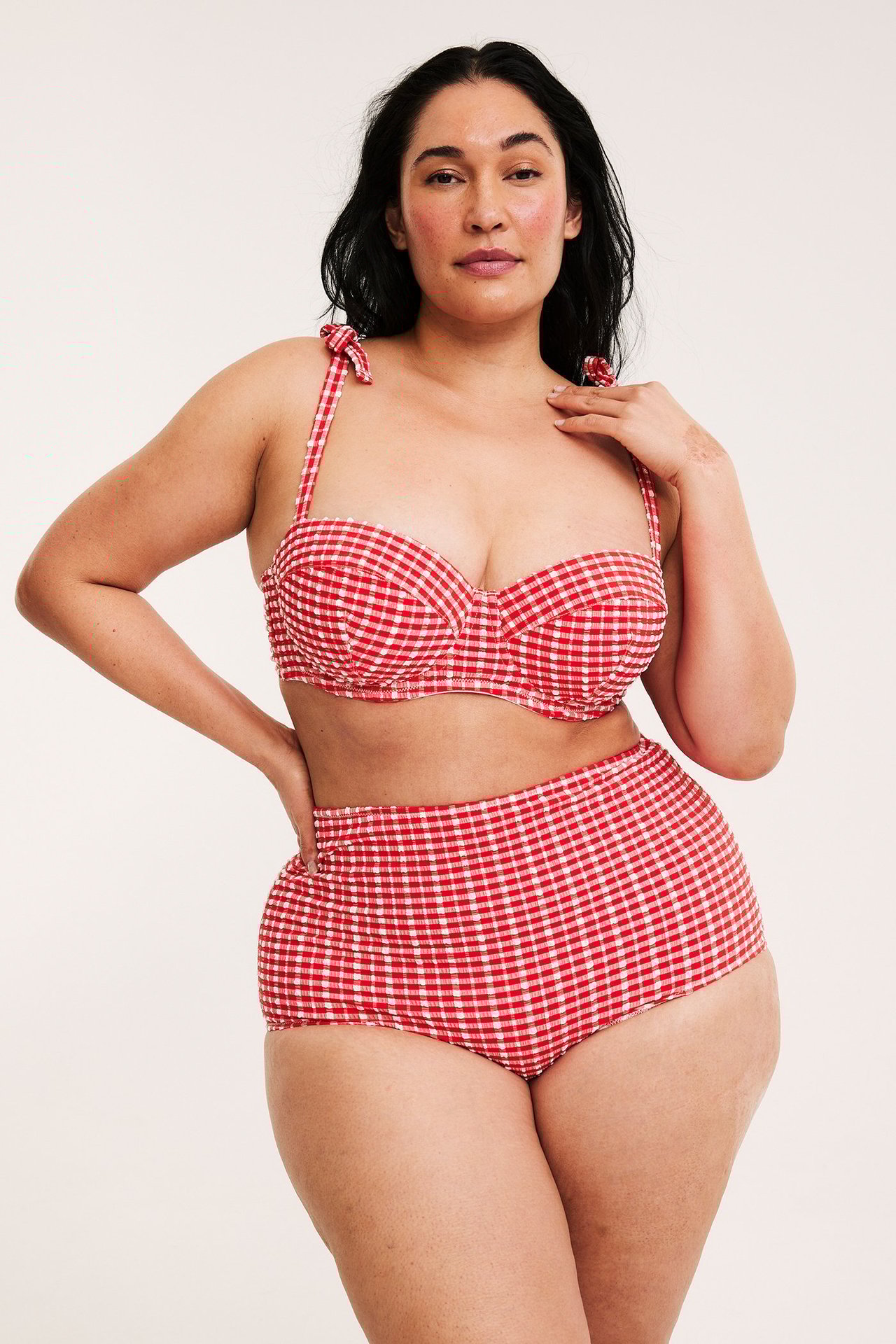 Widok z przodu: kobieta w czerwono-białych kratkowanych figach kąpielowych high hipster i dopasowanym biustonoszu.
