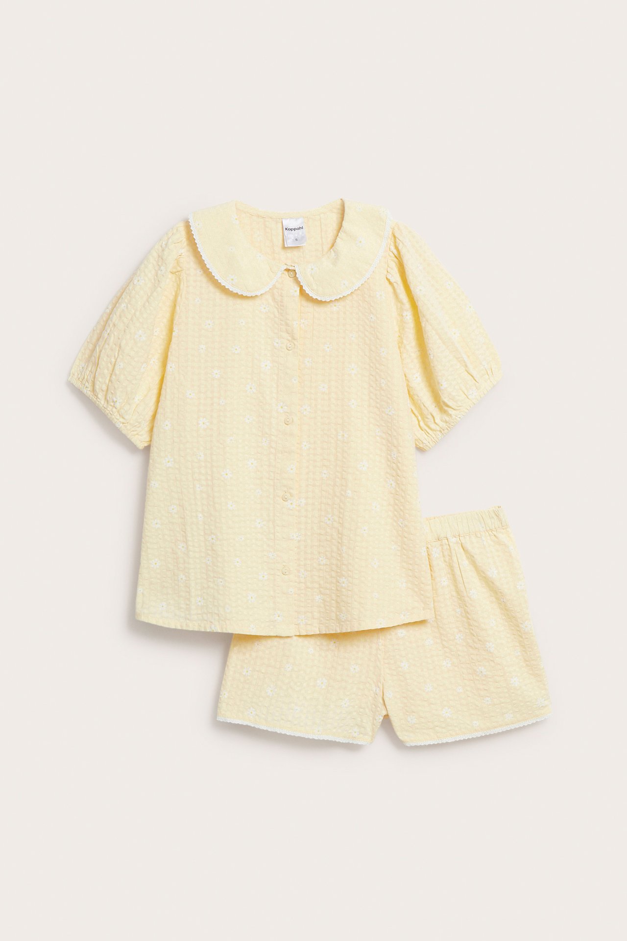Edestäpäin: Vaaleankeltainen kukkakuvioinen pyjamasetti, jossa pitsireunainen toppi ja shortsit.