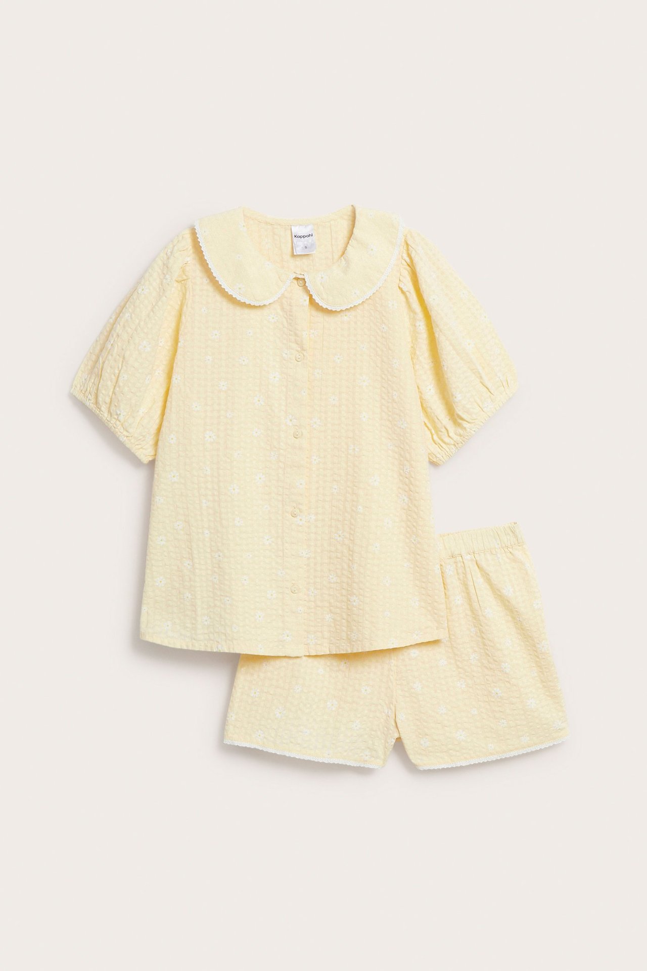 Edestäpäin: Vaaleankeltainen kukkakuvioinen pyjamasetti, jossa pitsireunainen toppi ja shortsit.