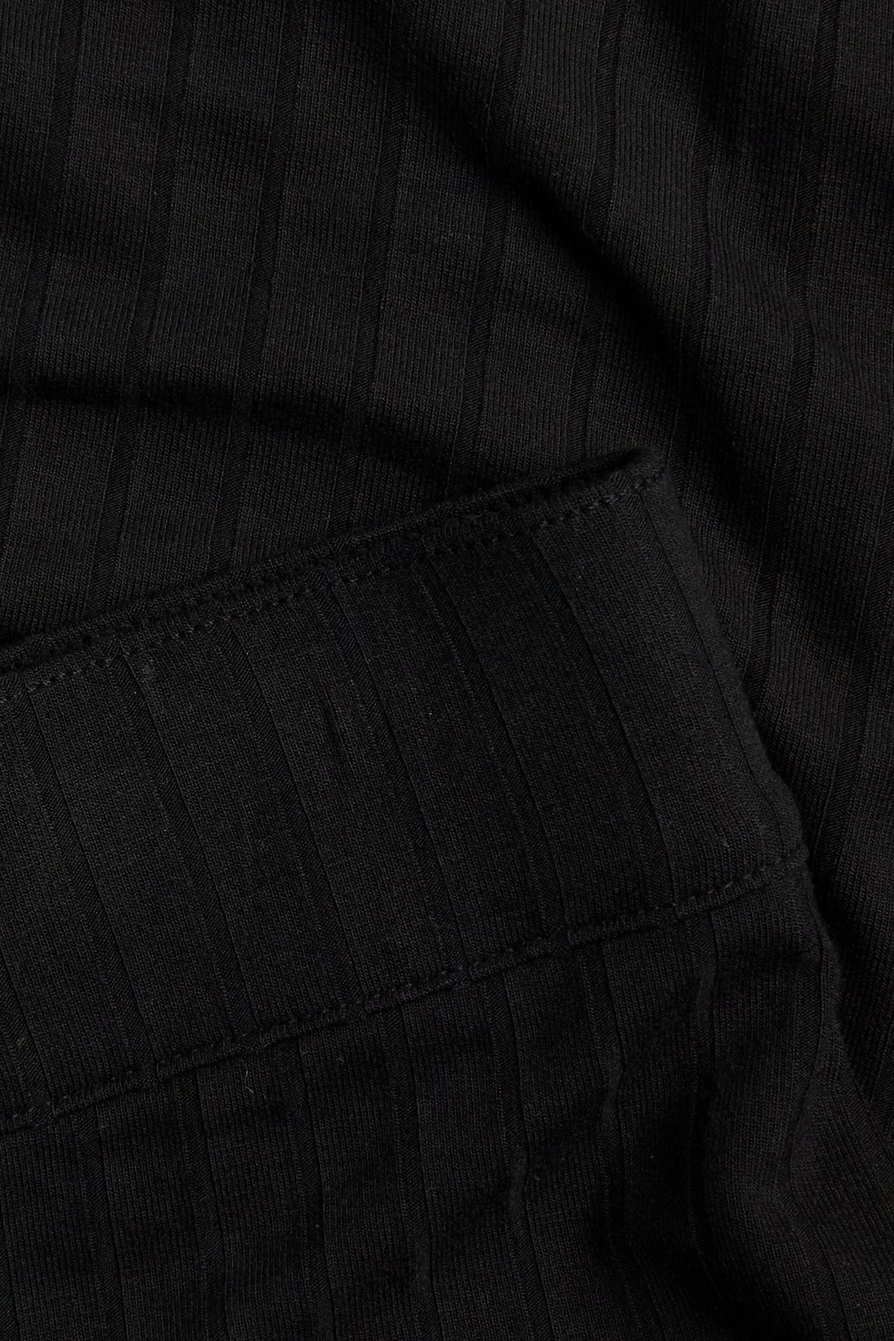 Närbild på en svart ribbad lång jerseykjol med resår i midjan.