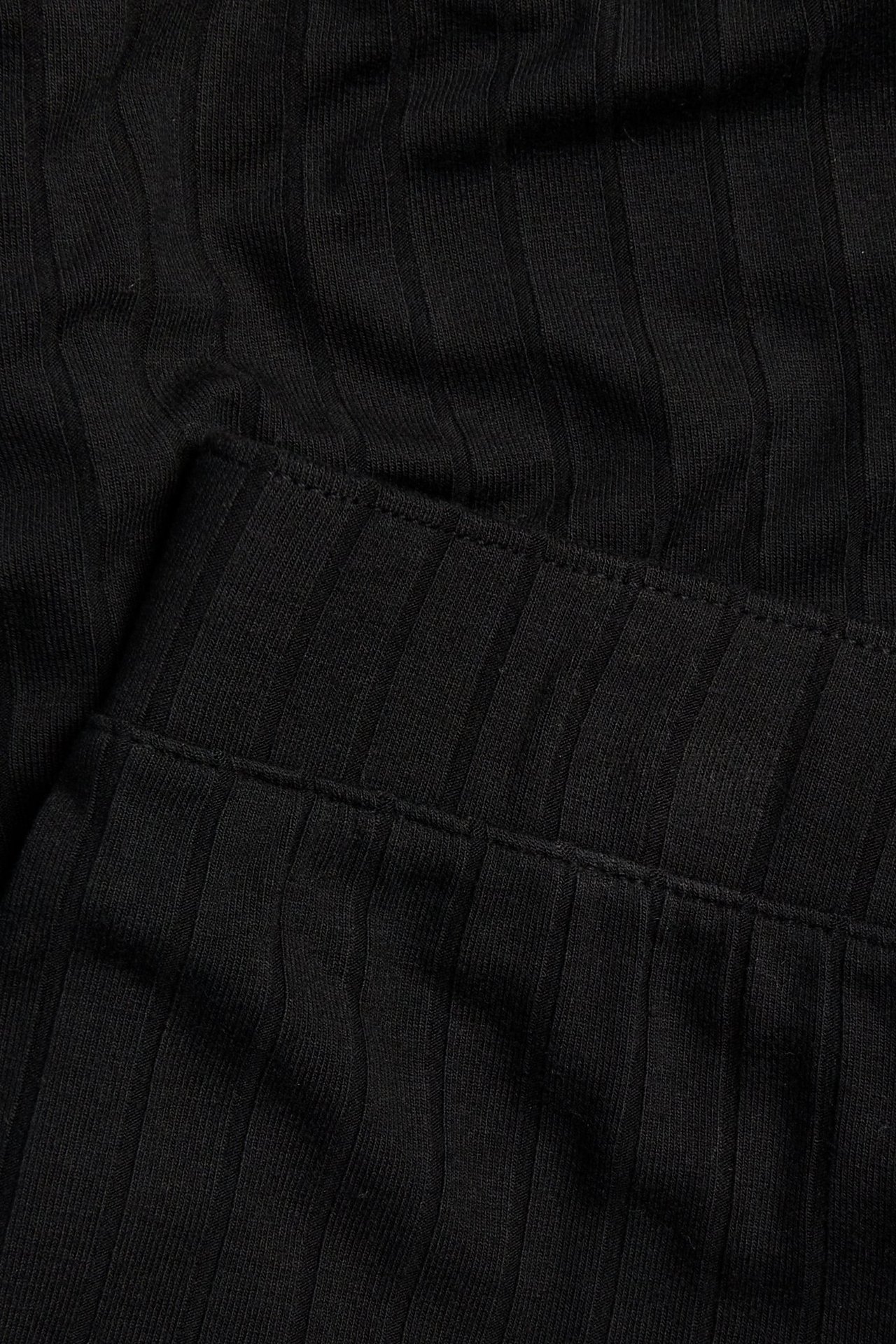 Zbliżenie czarnych, prążkowanych szerokich spodni z dżerseju wiskozowego z elastyczną talią.