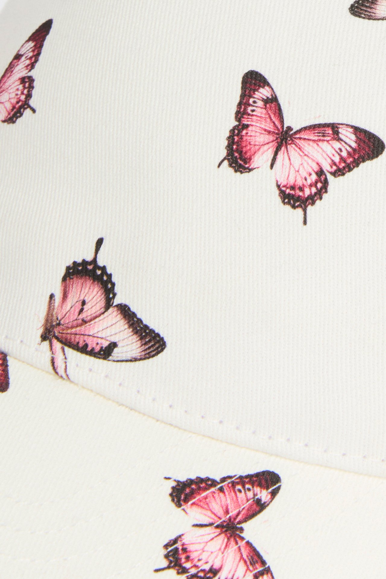 Zbliżenie na białą czapkę z różowym wzorem motyli.