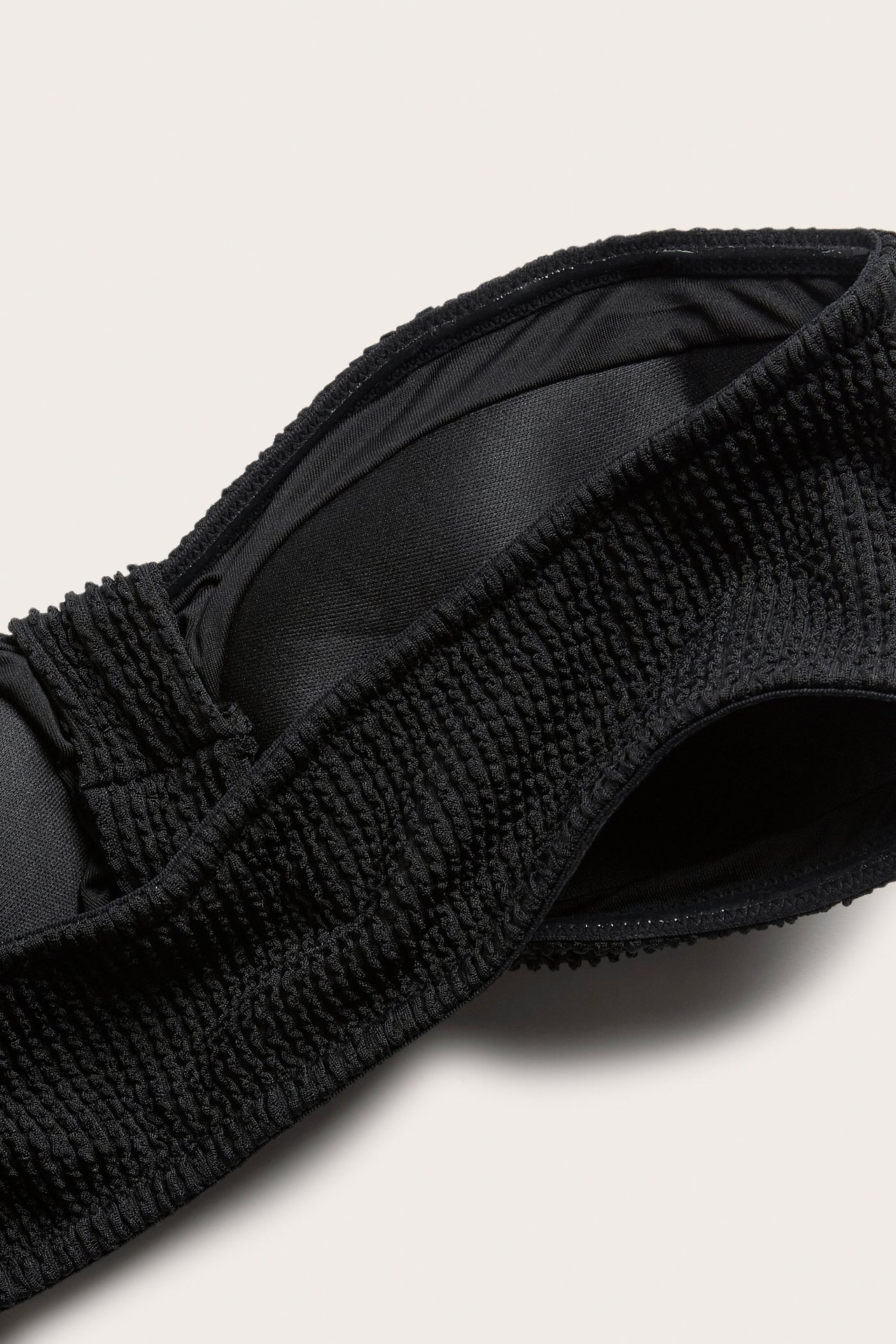 Zbliżenie na czarny teksturowany biustonosz kąpielowy typu bandeau z węzłem z przodu.