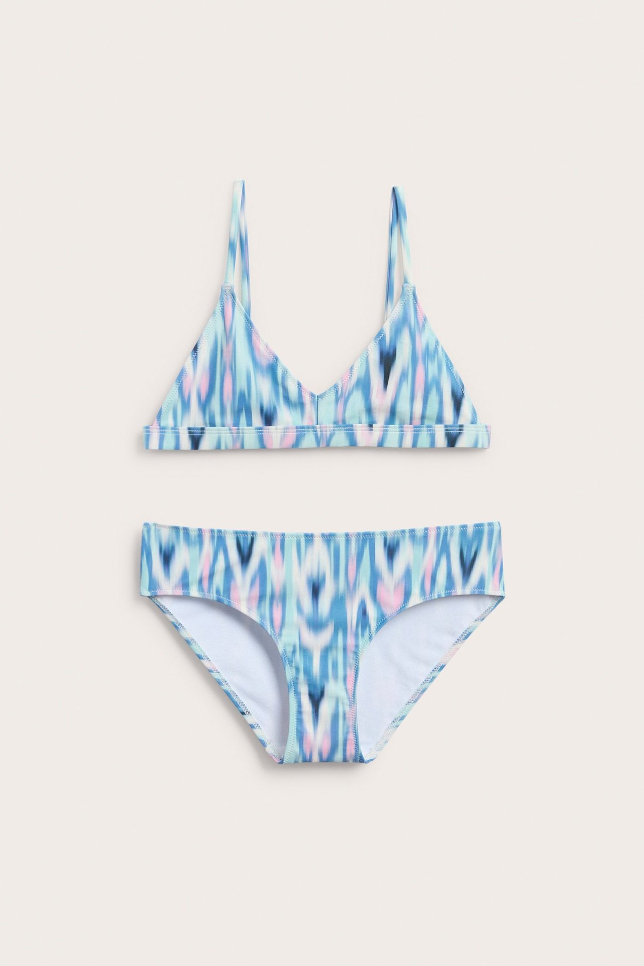 Widok z przodu dziecięcego wzorzystego bikini trójkątnego w kolorach jasnego turkusu, niebieskiego i różowego, z pasującymi figami.