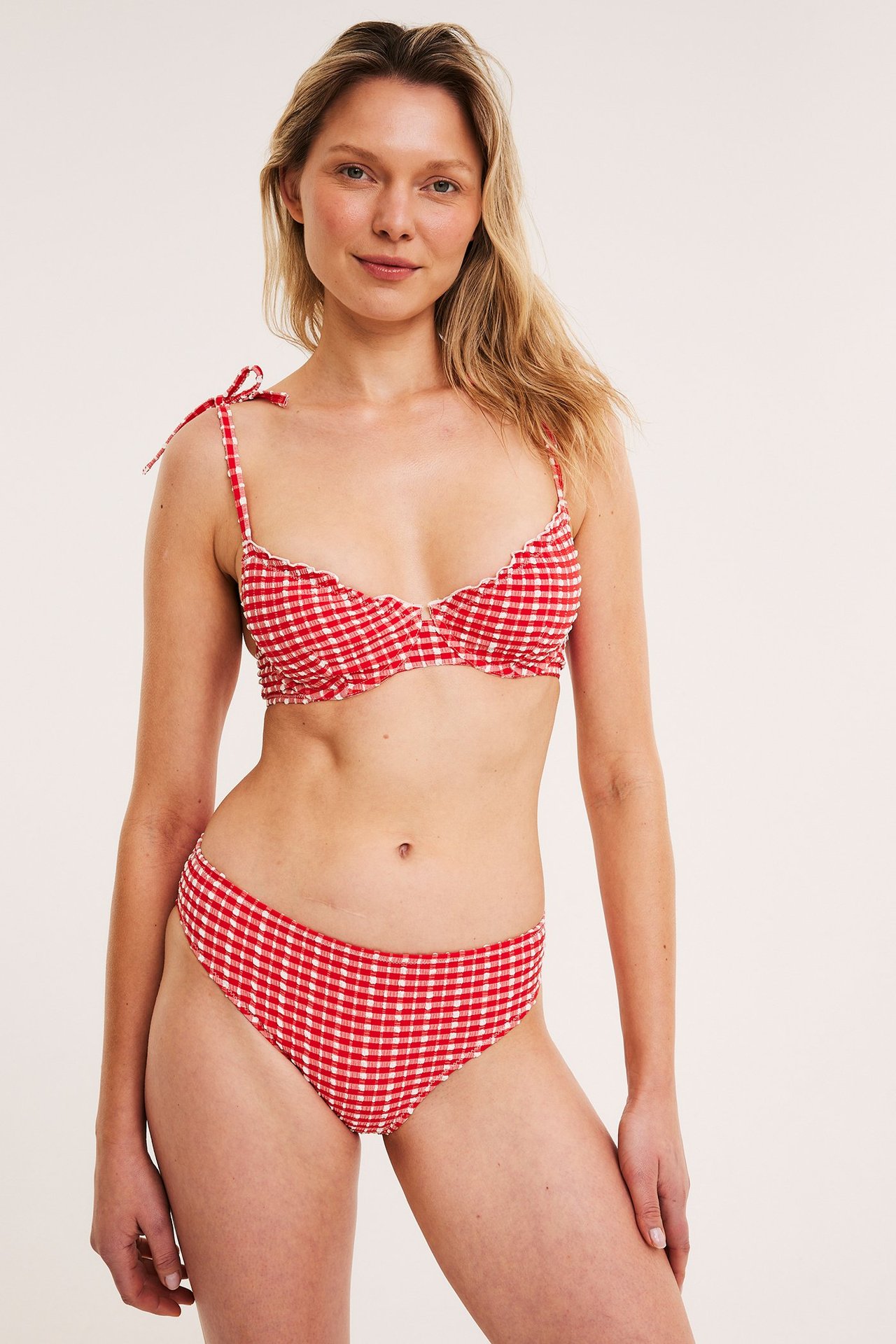 Edestä: Nainen punavalkoruudullisissa bikinihousuissa ja yhteensopivassa narubikinirintaliiveissä.