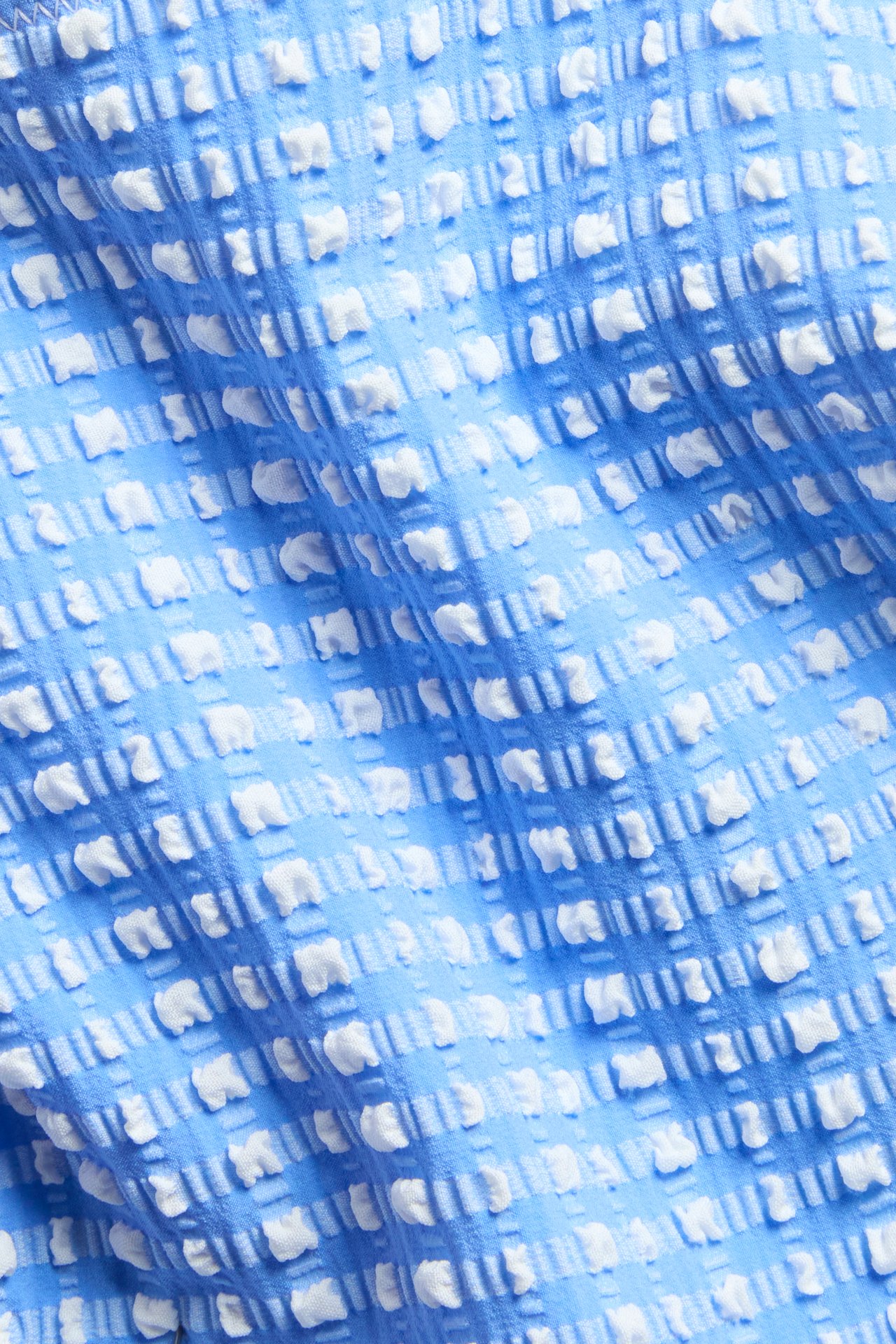 Lähikuva sinisestä bikinityylistä, jossa on valkoinen kuvioitu ruutukuvio.