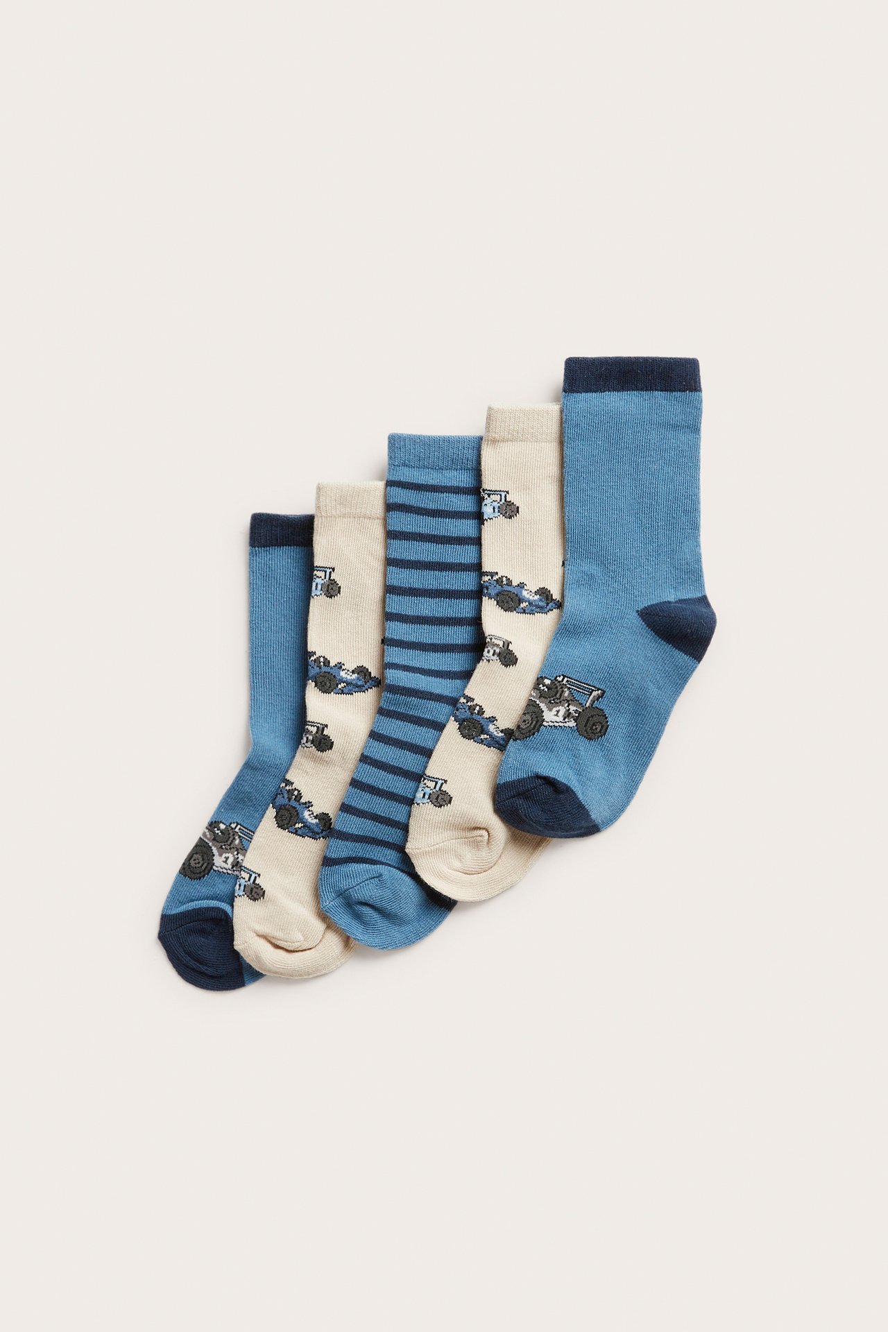 Platt lay av fem par barnstrumpor i blått och beige med racerbilsmönster och blå ränder.