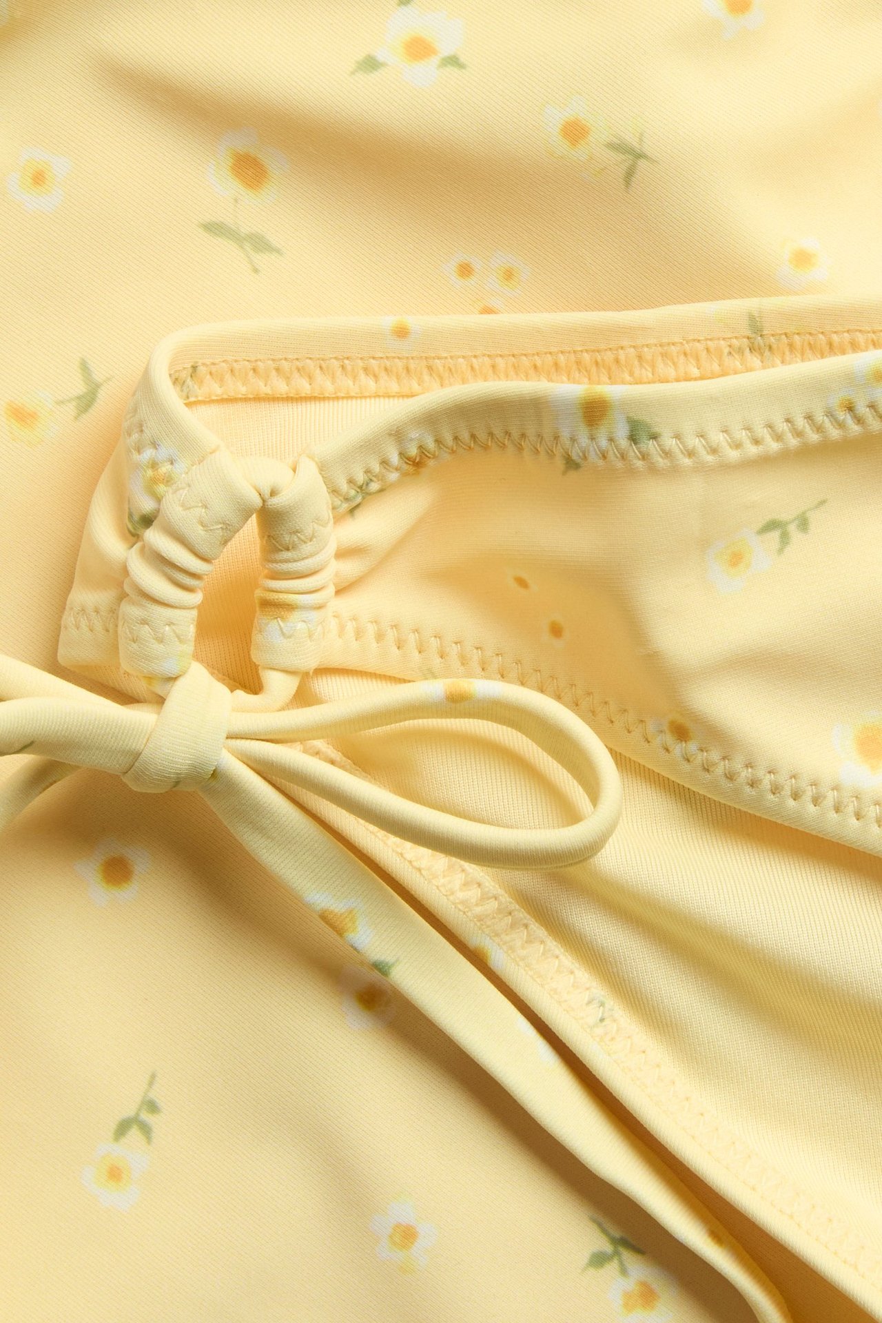 Närbild av en gul mönstrad bikiniunderdel med knytband, gjord av baddräktstyg.