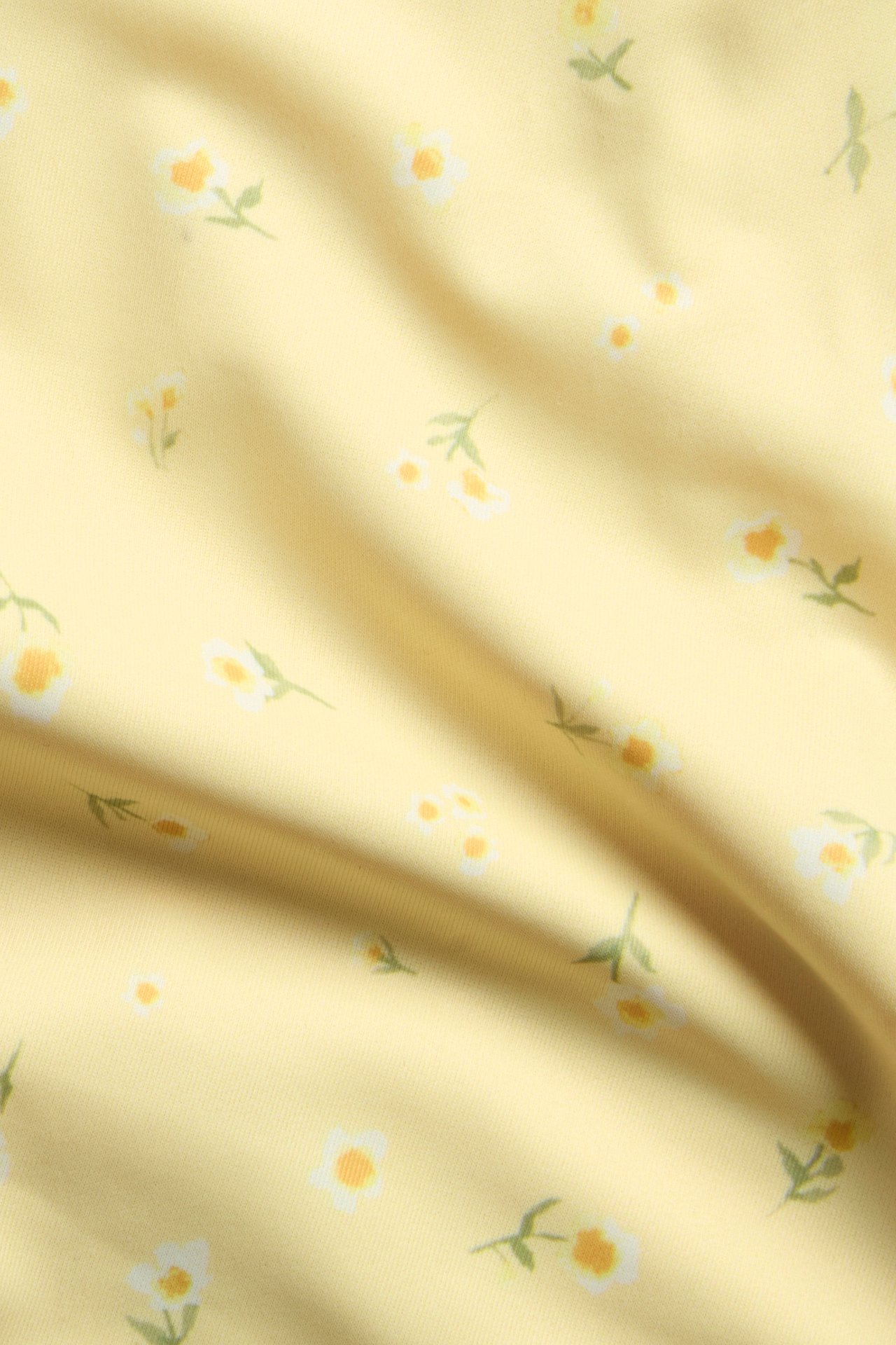 Närbild på gult bikinitrosatyget med ett mönster av små vita och gula blommor.