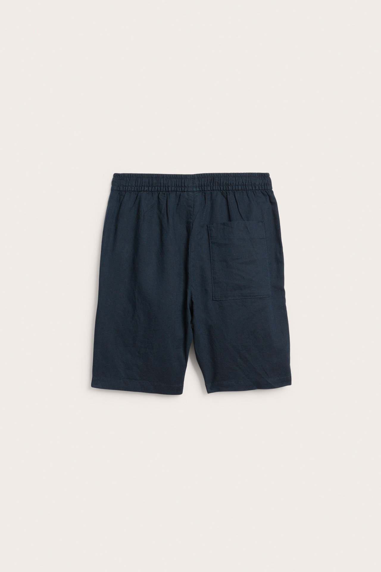 Tummansiniset pellavasekoiteshortsit joustavalla vyötäröllä ja yhdellä takataskulla, takaa.