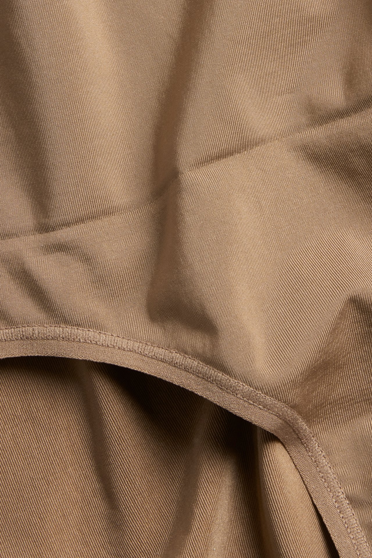 Lähikuva ruskeista muotoilevista alushousuista, valmistettu sileästä polyamidisekoitteesta ja näkyvillä elastisilla saumoilla.