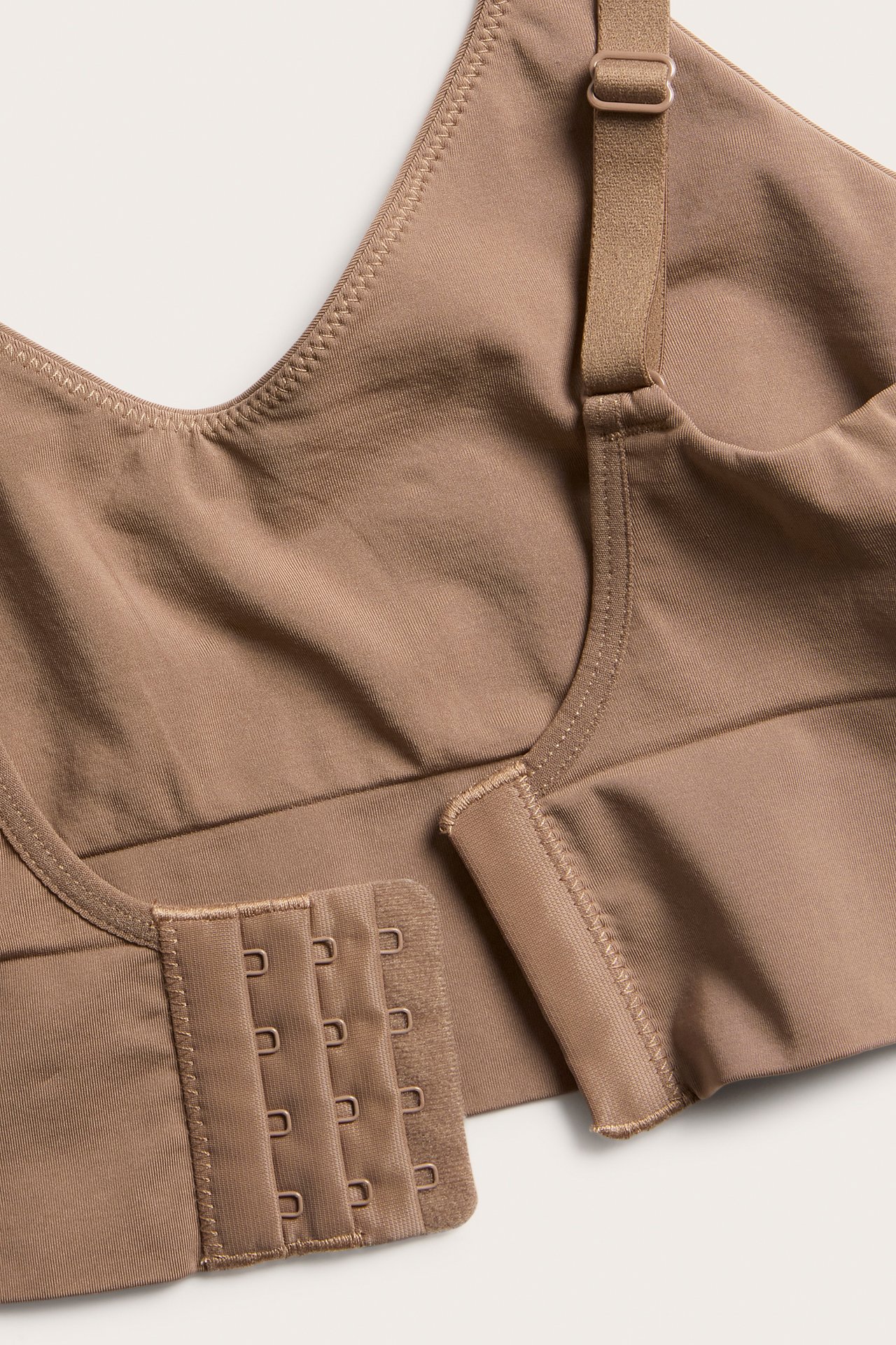 Lähikuva ruskeasta saumattomasta rintaliivistä, jossa säädettävät olkaimet ja 4x3 hakaskiinnitys.