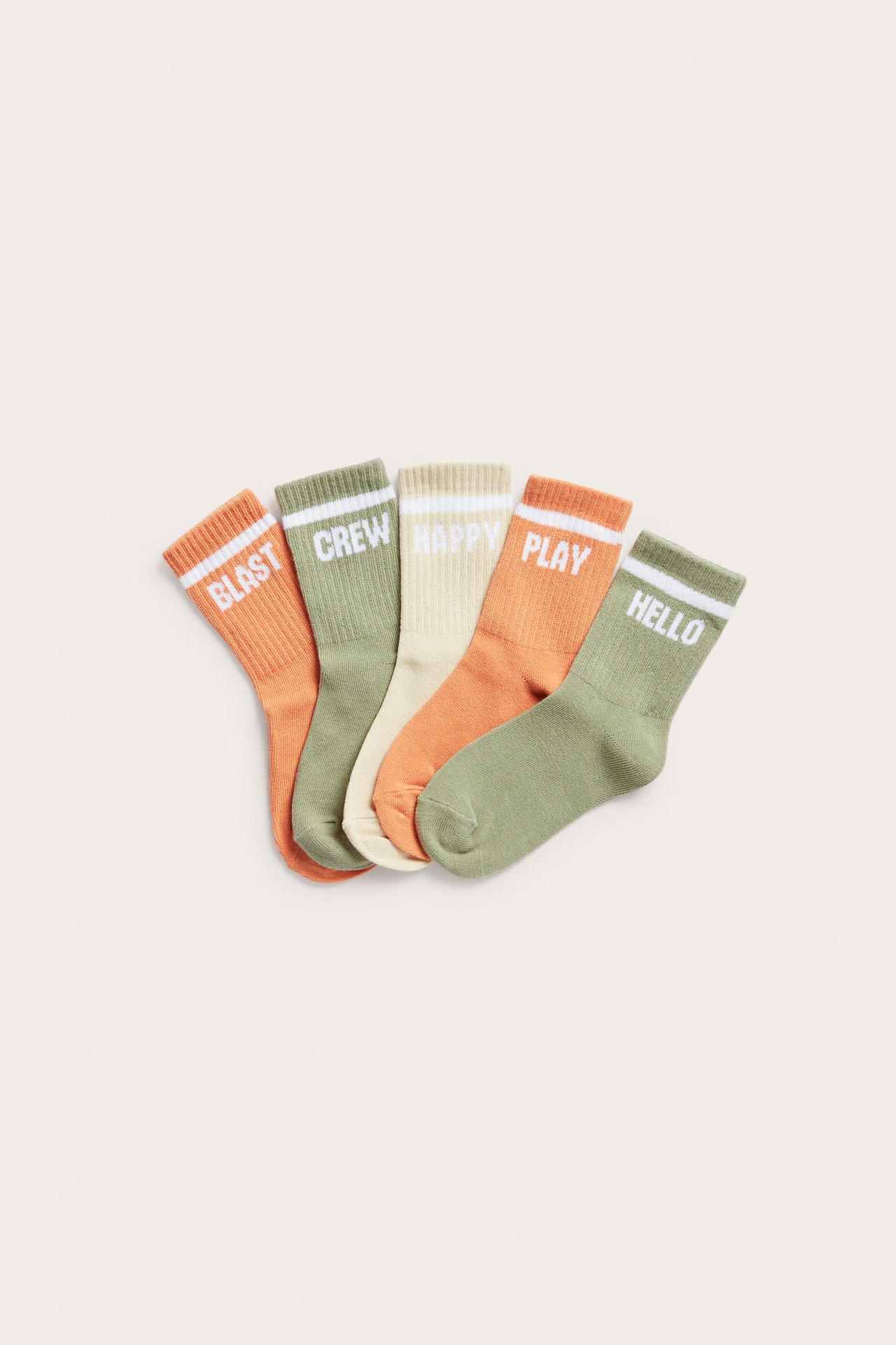 Uppifrån vy av fem barnstrumpor med ribbad mudd: orange, ljusgrön, krämvit, med vit text och ränder.