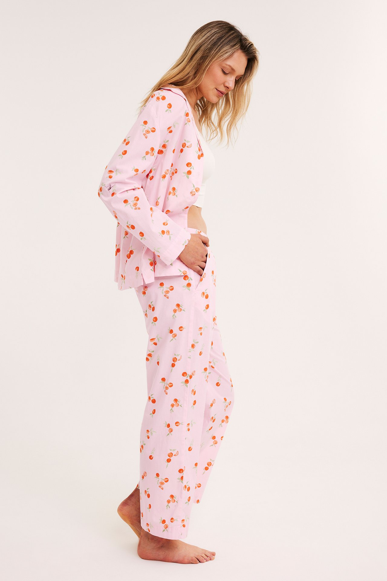 Sivukuva: nainen vaaleanpunaisissa kirsikkakuvioisissa pyjamahousuissa joustovyötäröllä ja yhteensopivassa takissa.