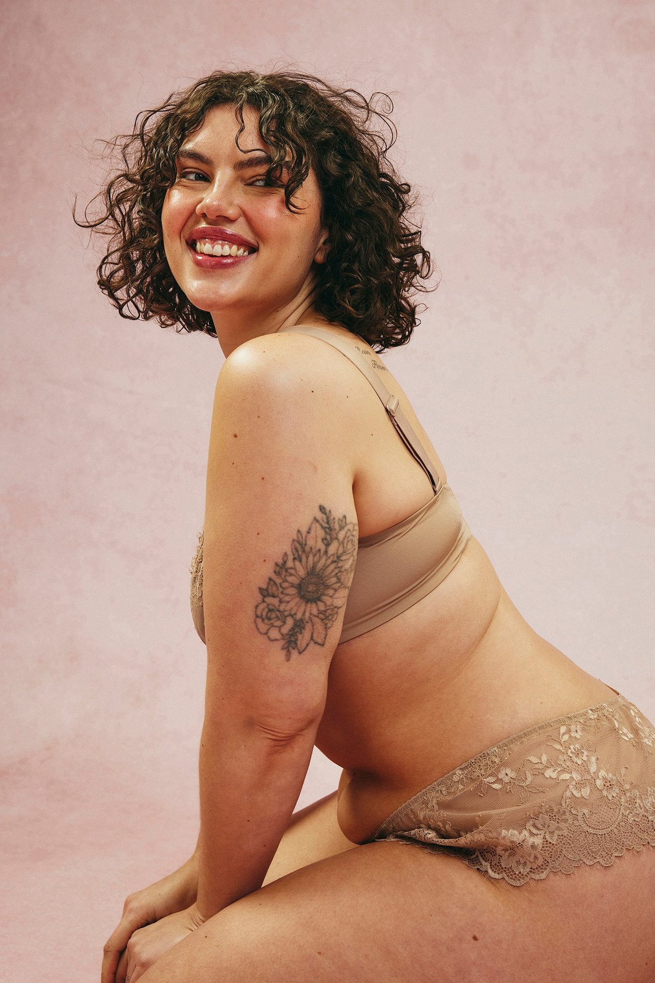 Front-sidovy av en kvinna i högskurna bruna spetsbrieftrosor med matchande brun BH.
