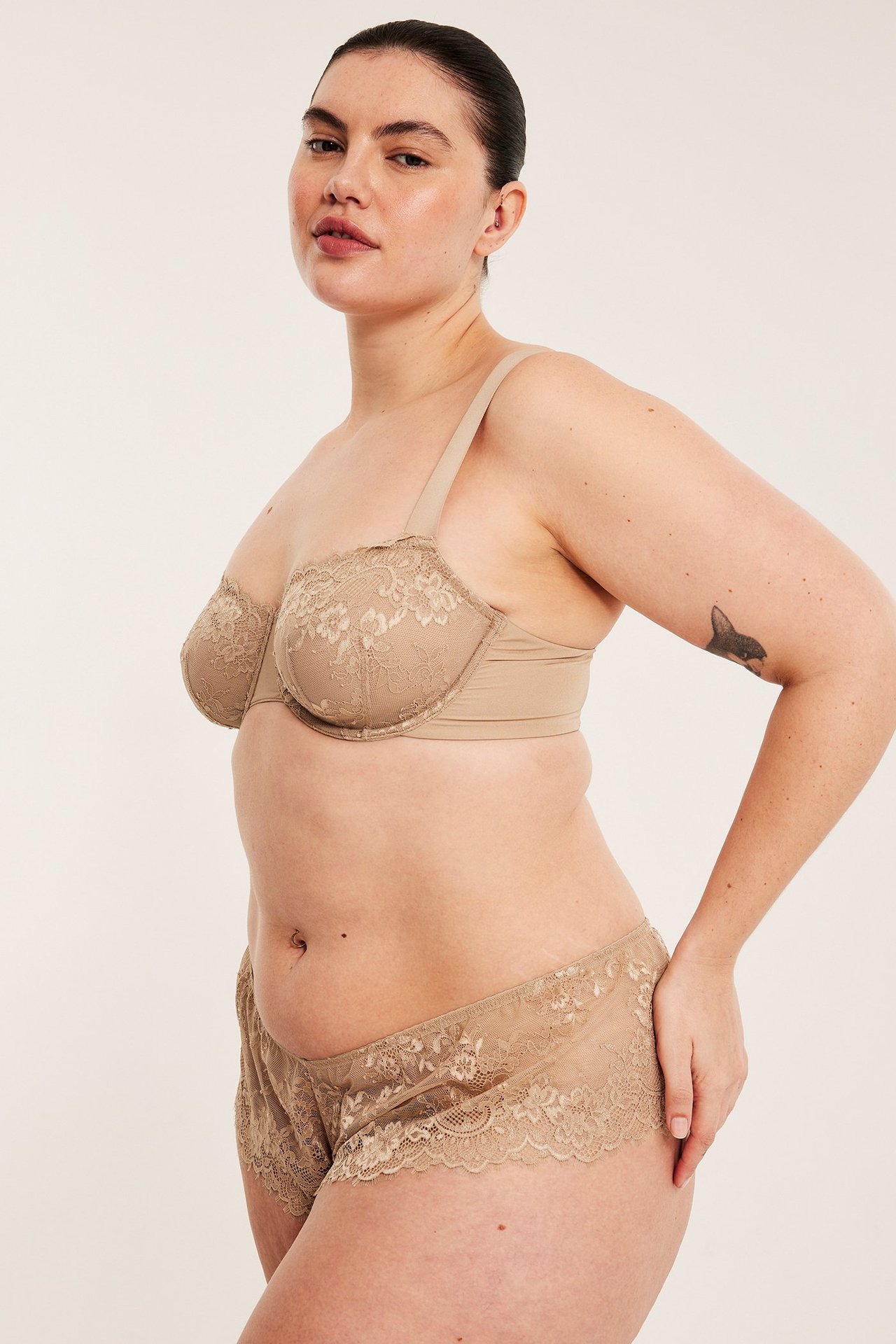 Naisen sivukuva, yllään ruskeat pitsibrieftrosat ja yhteensopivat pitsirintaliivit.