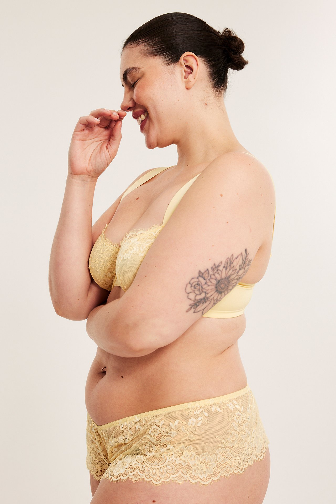Widok z boku kobiety w jasnożółtych koronkowych figach i pasującym biustonoszu.