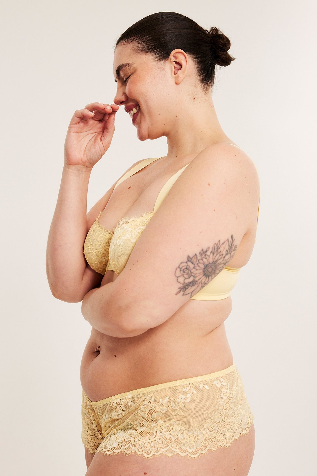 Widok z boku kobiety w jasnożółtych koronkowych figach i pasującym biustonoszu.