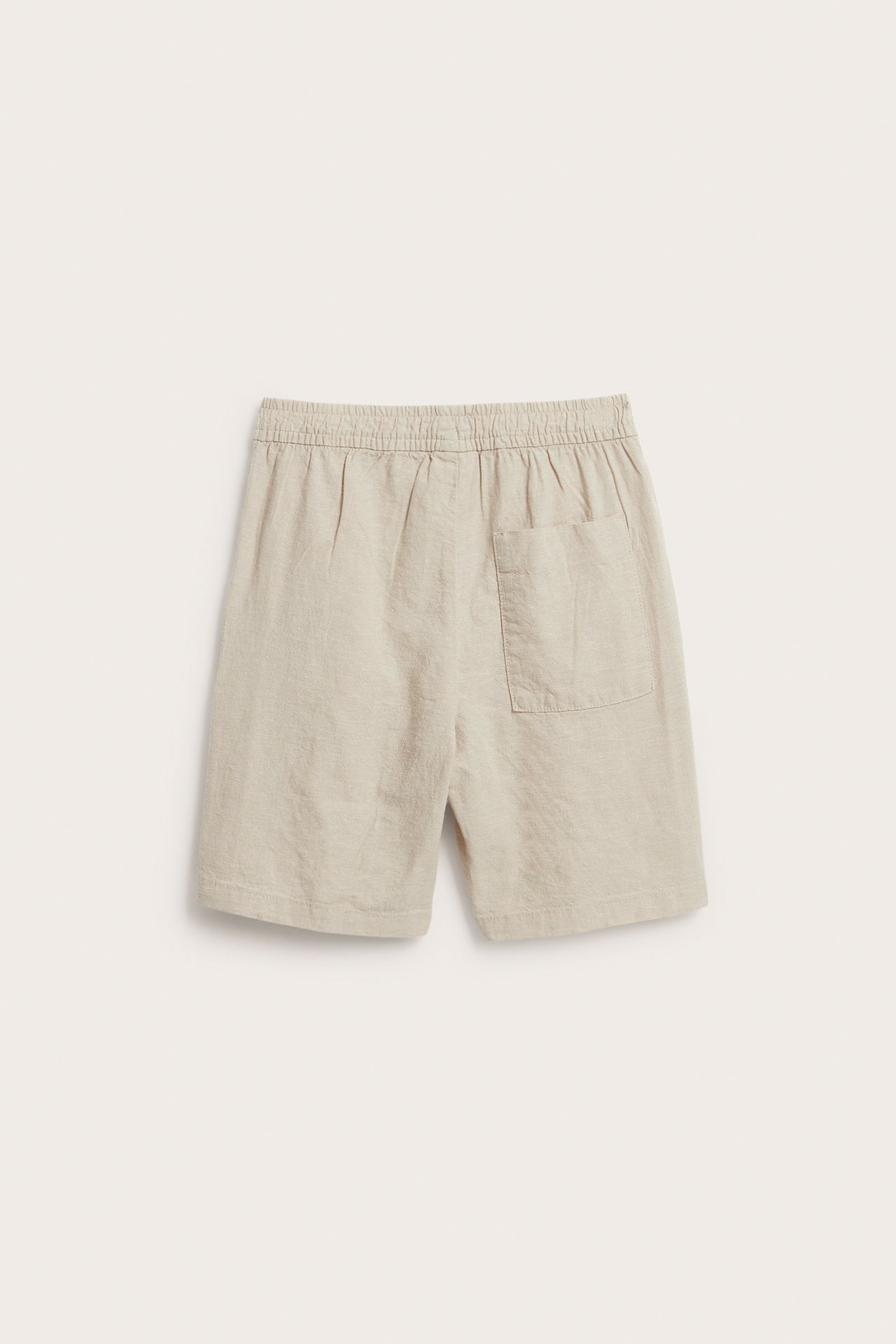 Takaa: beiget lasten pellavasekoiteshortsit joustavalla vyötäröllä ja yhdellä takataskulla.
