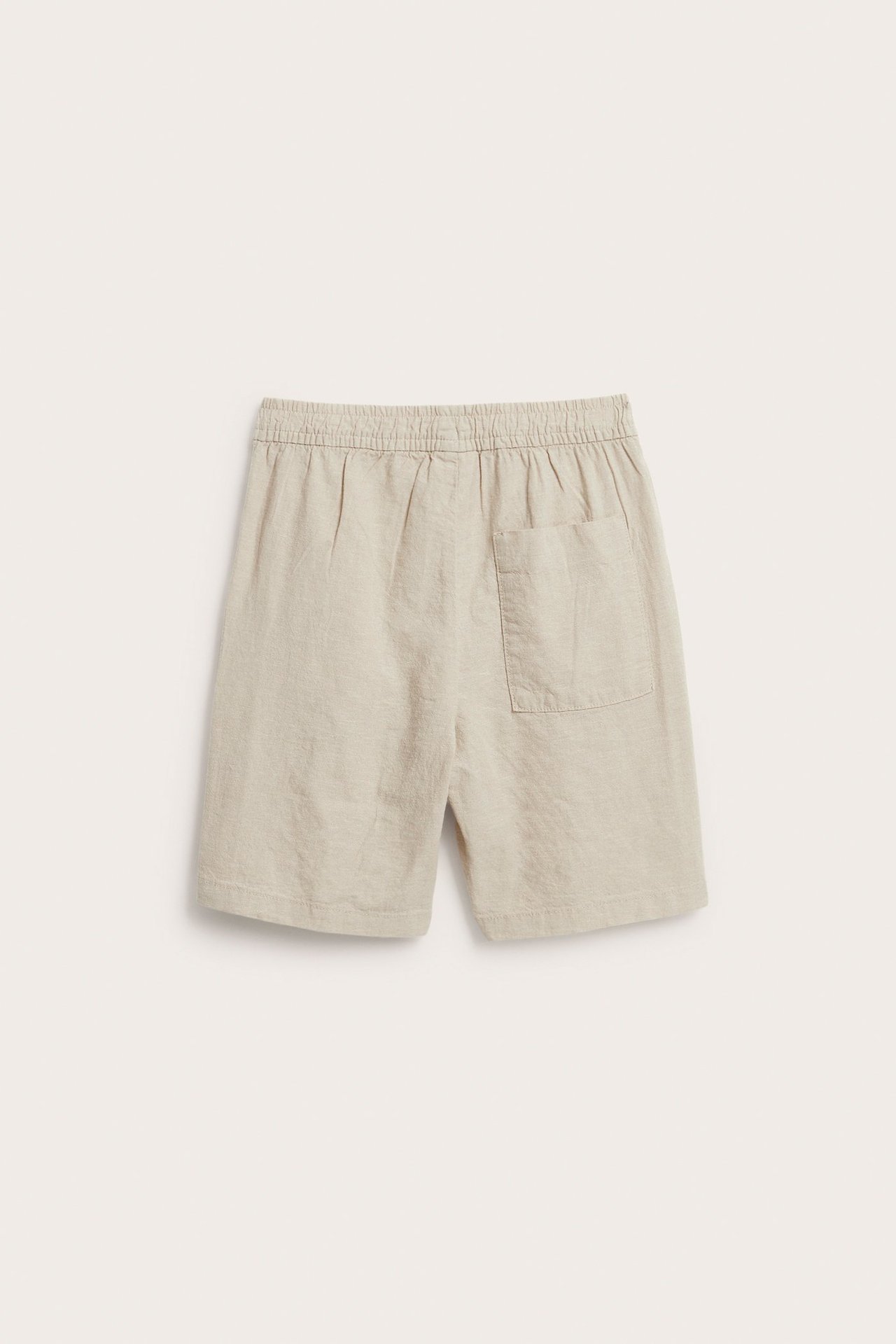Takaa: beiget lasten pellavasekoiteshortsit joustavalla vyötäröllä ja yhdellä takataskulla.