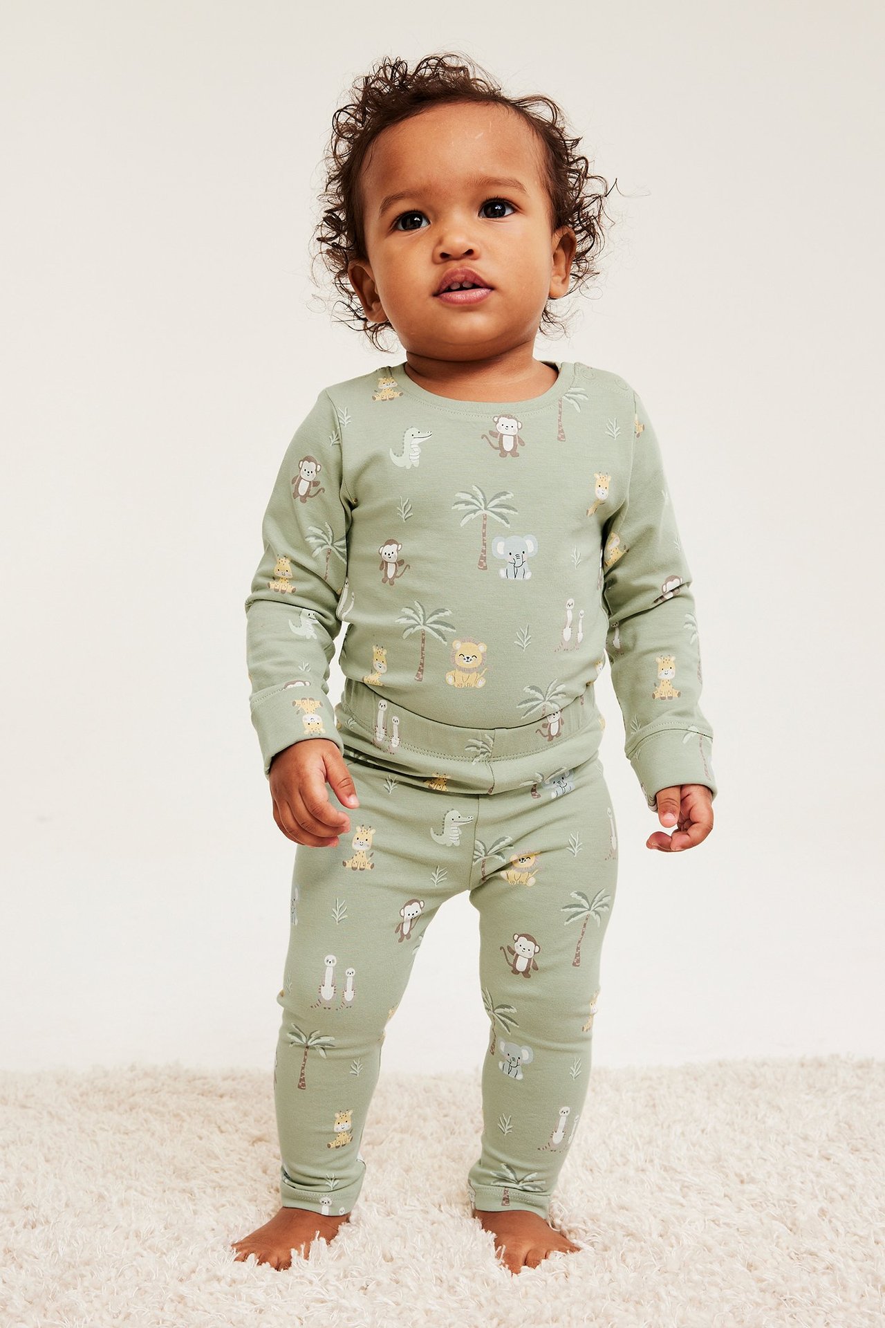 Vauva edestä: vihreä pitkähihainen paita ja yhteensopivat housut eläinkuviolla.