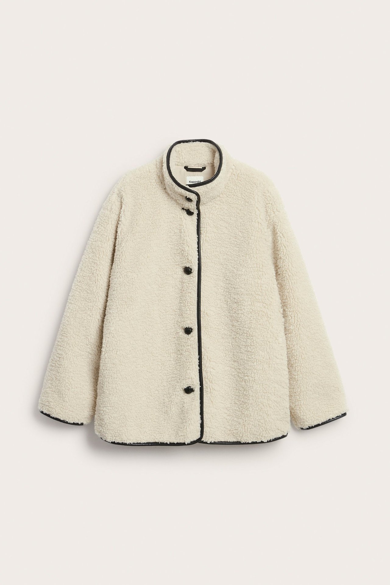 Edestä luonnonvalkoinen piletakki korkealla kauluksella, mustilla napeilla ja reunuksilla.