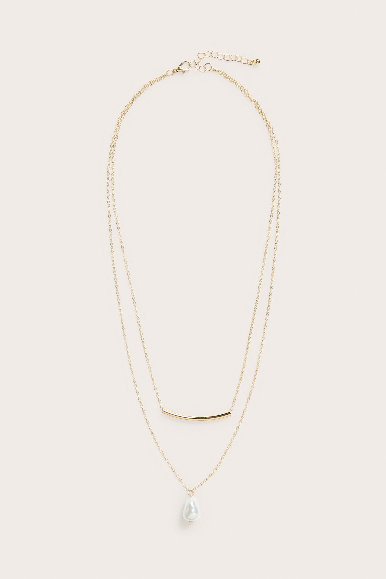 Widok z przodu: złoty zestaw dwóch naszyjników z zakrzywionym prętem i perłową zawieszką.