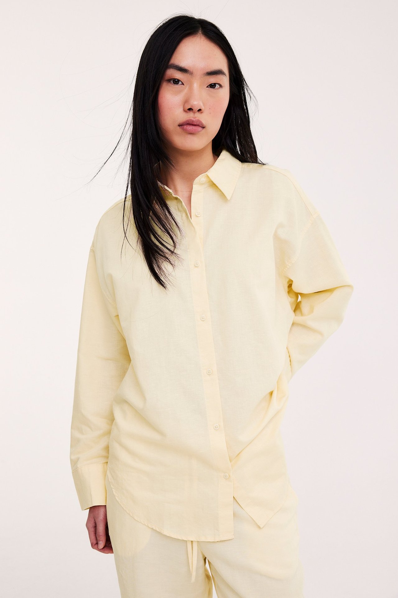 Widok z przodu kobiety w jasnożółtej koszuli oversize z mieszanki lnu i pasujących spodniach.