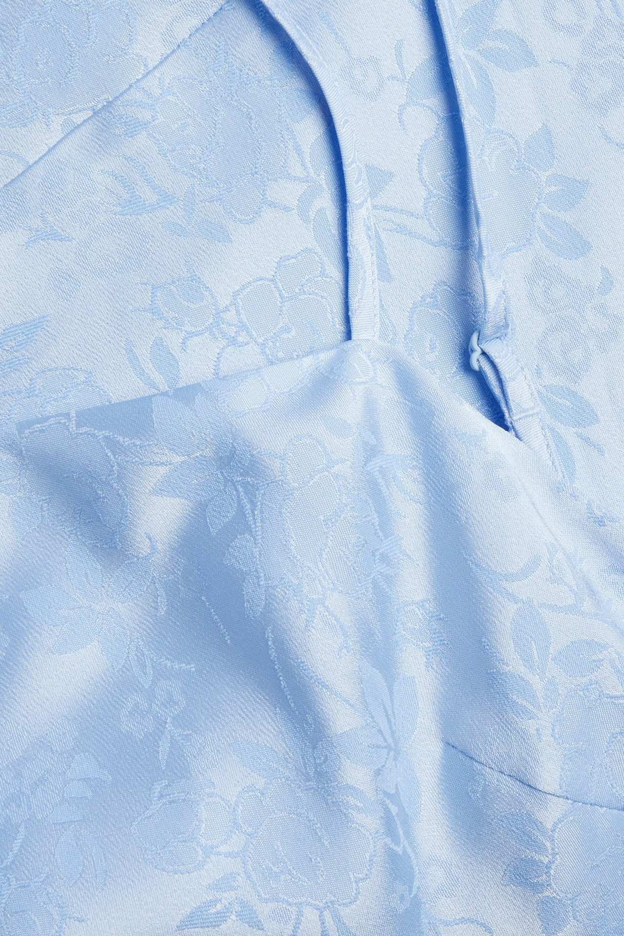 Nærbilde av lyseblå jacquard slipkjolestoff med blomstermønster og en tynn stropp.