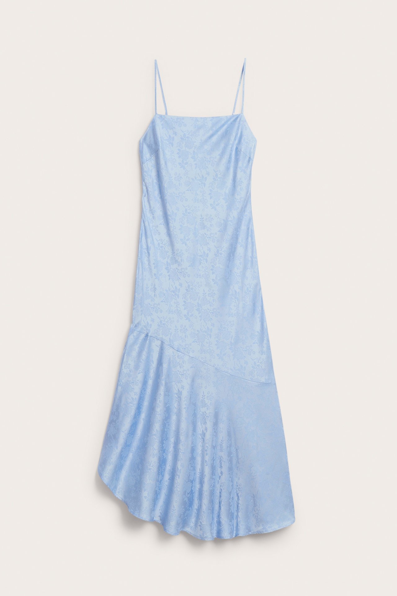 Frontvisning av en lyseblå jacquard-slipkjole med tynne stropper og asymmetrisk diagonal nederkant.