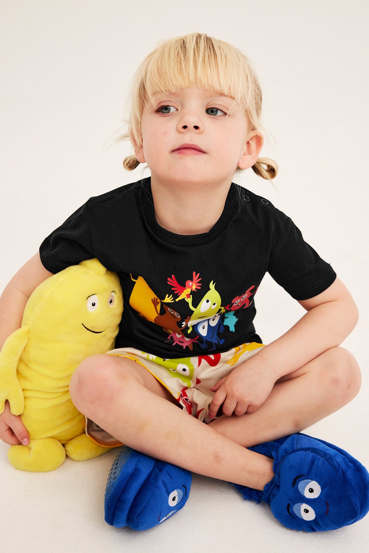 Dziecko w czarnym bawełnianym T-shircie z nadrukiem Babblarna, siedzi.