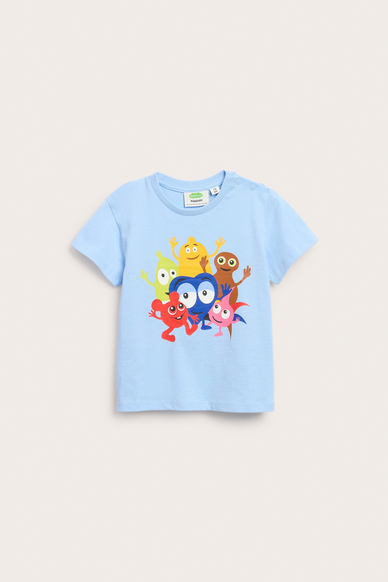 Frontvy: Ljusblå bomulls-t-shirt för barn med färgglatt Babblarna-tryck och axelknappar.