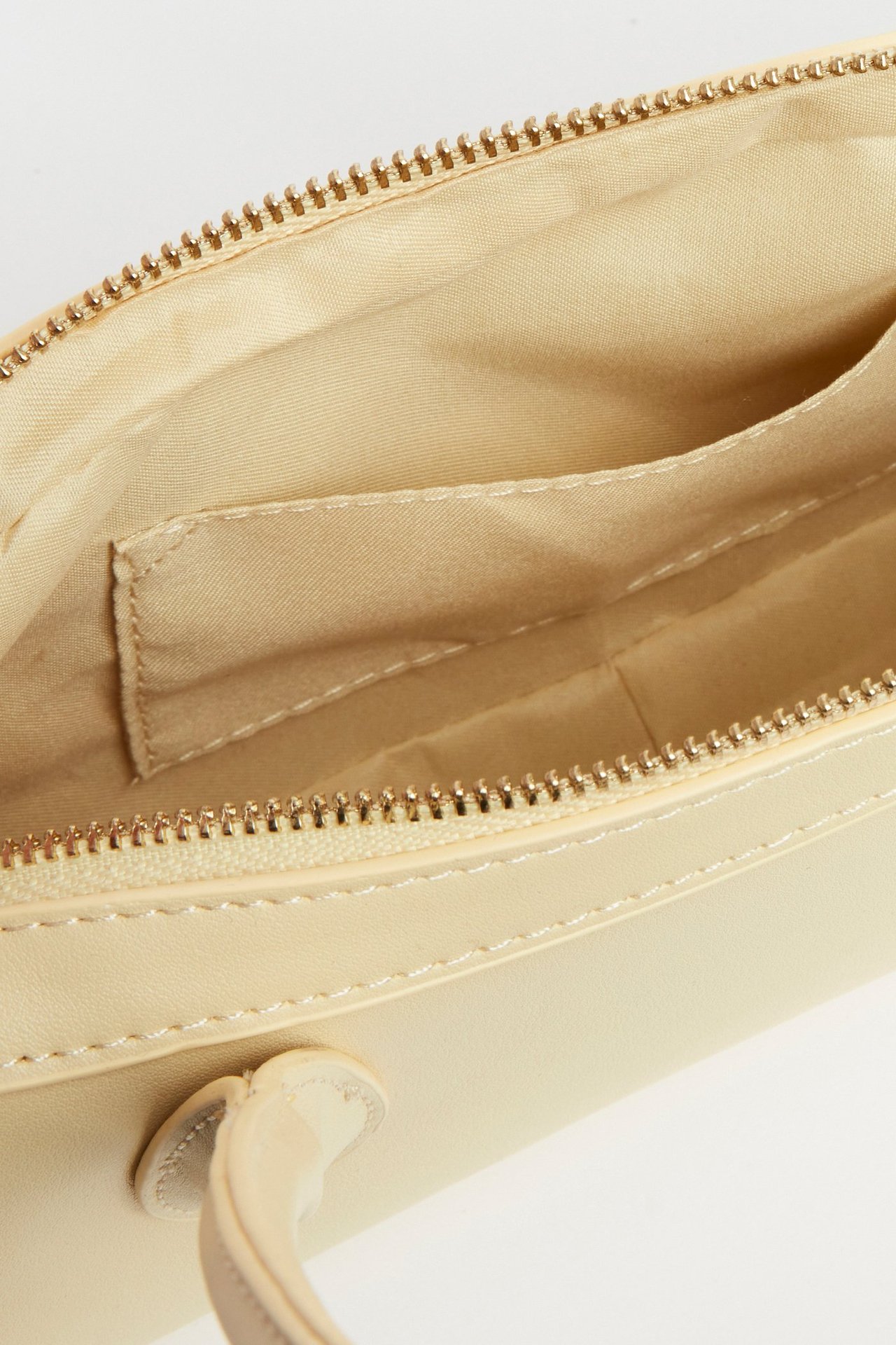 Nærbilde av en åpen lysegul bowlingveske med gullfarget glidelås og synlige innerlommer.