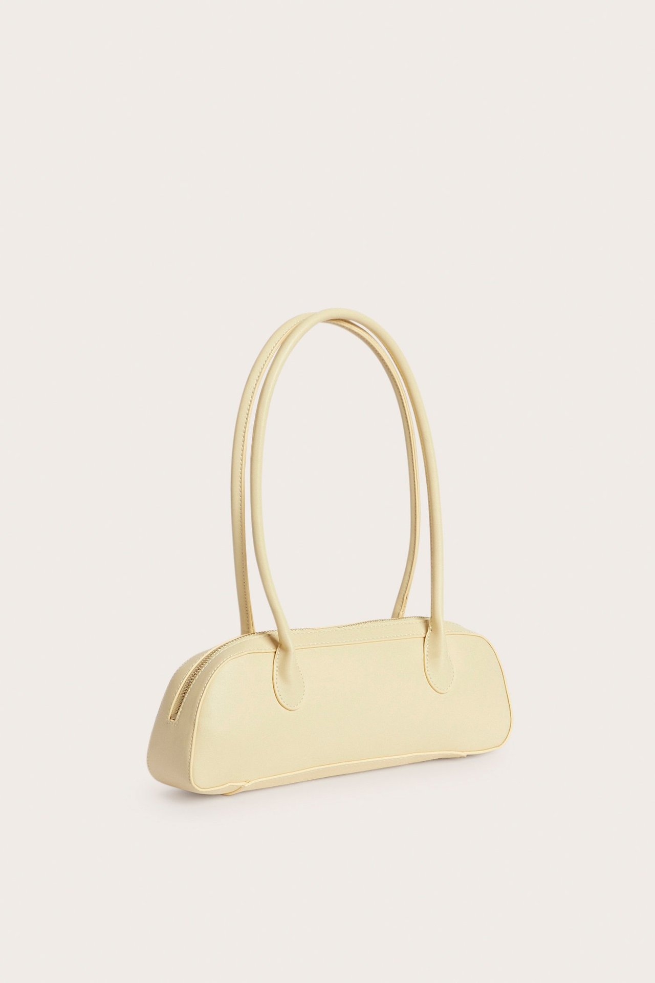 Edestäpäin: vaaleankeltainen pitkulainen bowlinglaukku vetoketjulla ja kahdella pitkällä kantokahvalla.