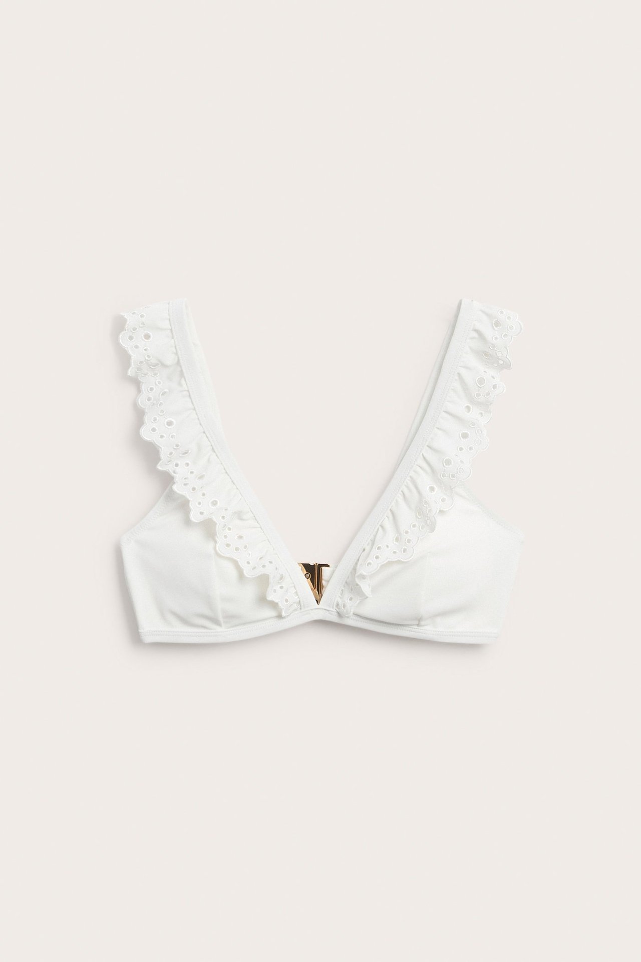 Frontvy: Offwhite bikinitopp med V-hals, volanger, broderie anglaise-detaljer og en gullfarget V-lås.
