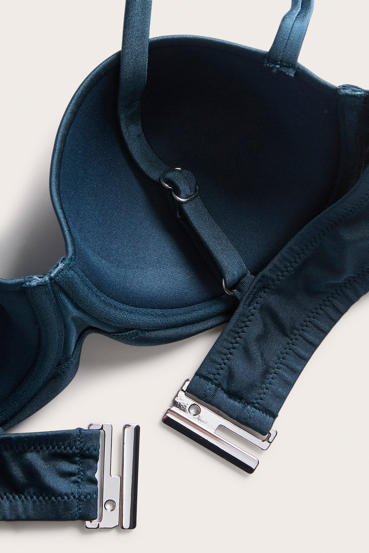 Nærbilde av en mørkeblå ensfarget balconette-bikini-BH med fast vattering, justerbare stropper og sølvfarget spenne.