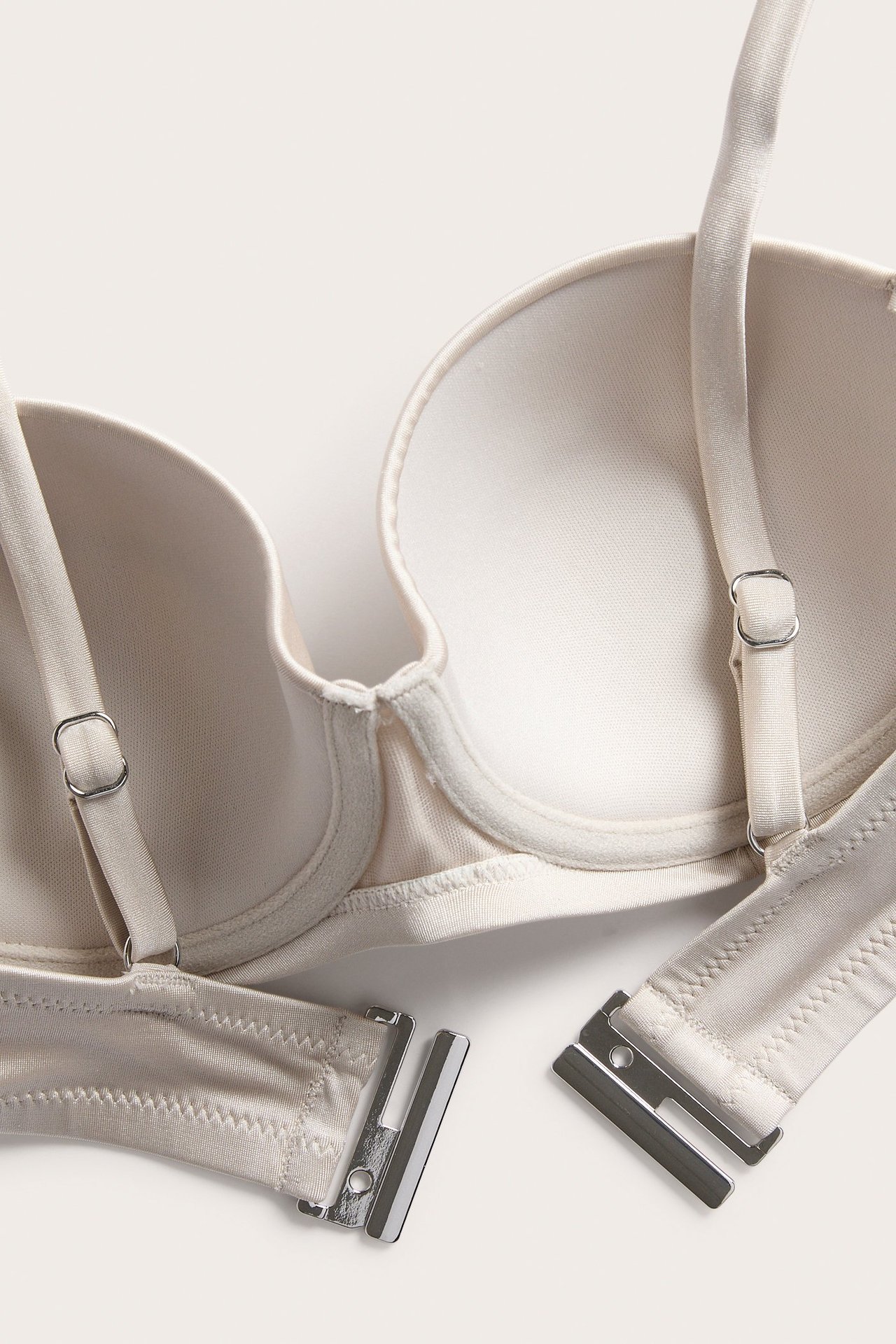 Lähikuva beigestä balconette-bikiniyläosasta, jossa on topatut kupit, säädettävät olkaimet ja metallilukko.