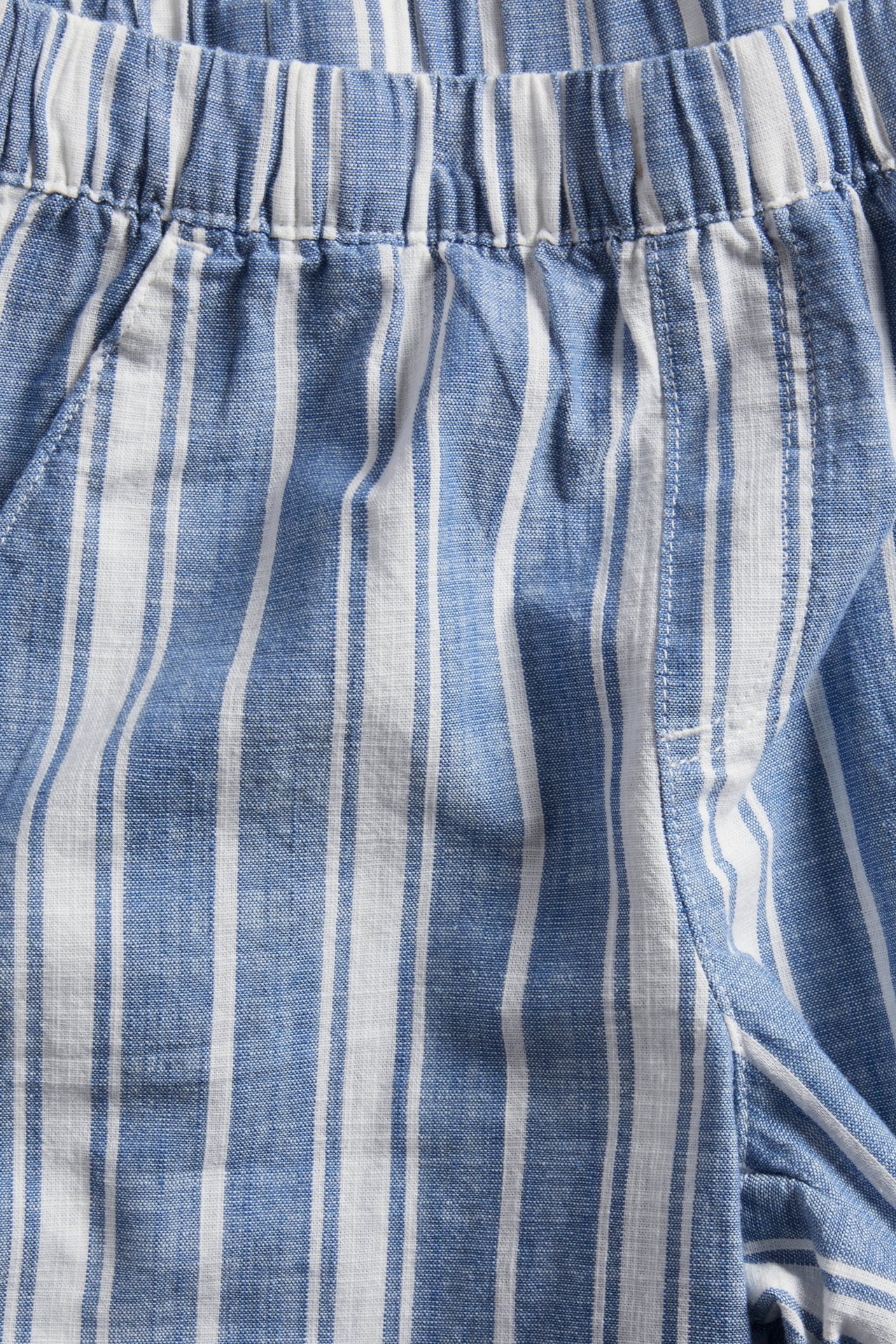 Widok z przodu na dziecięce granatowo-białe bawełniane szorty w paski z elastyczną talią.